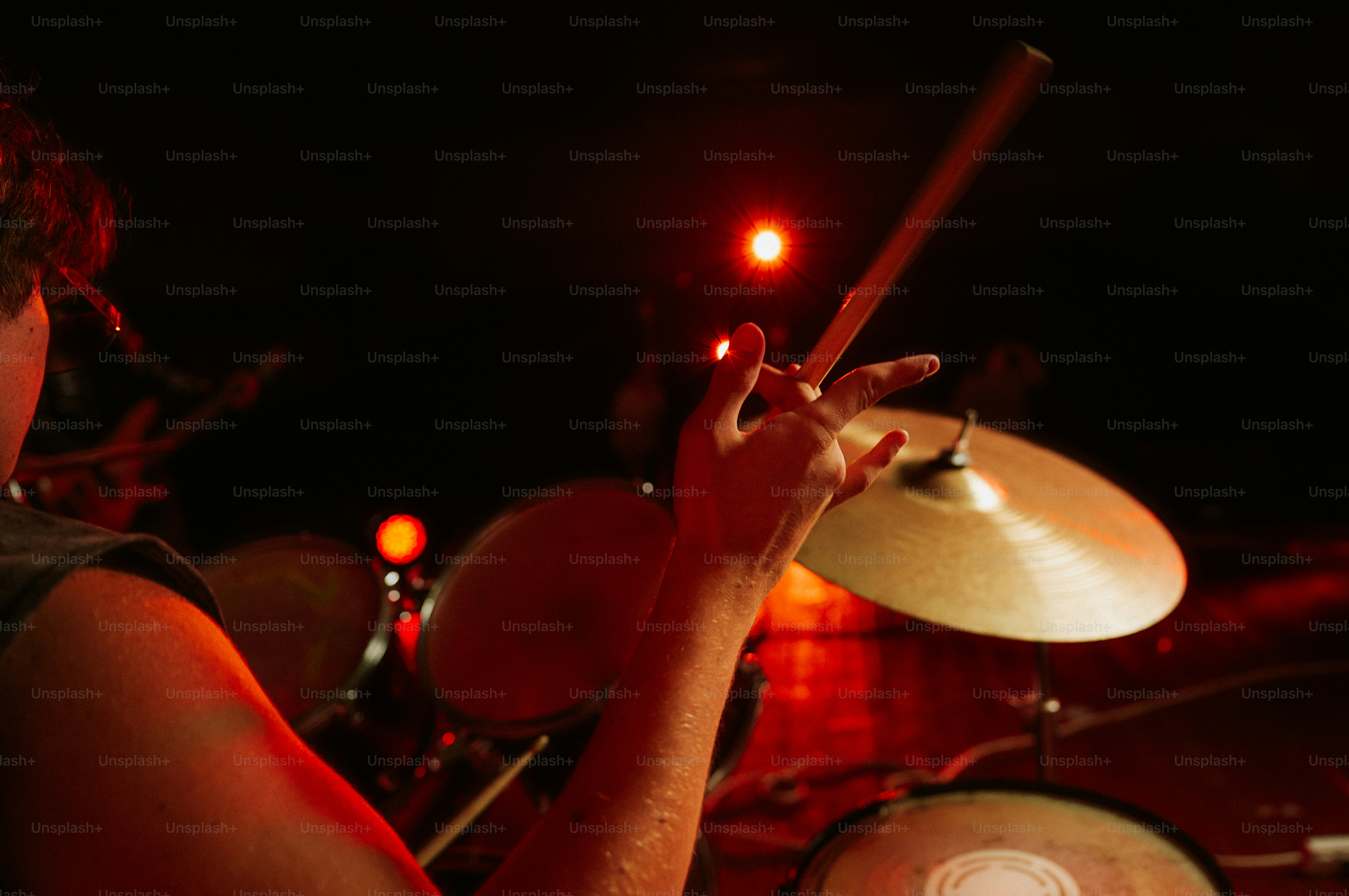 A drummer holding a stick over a cymbal in a dimly lit room