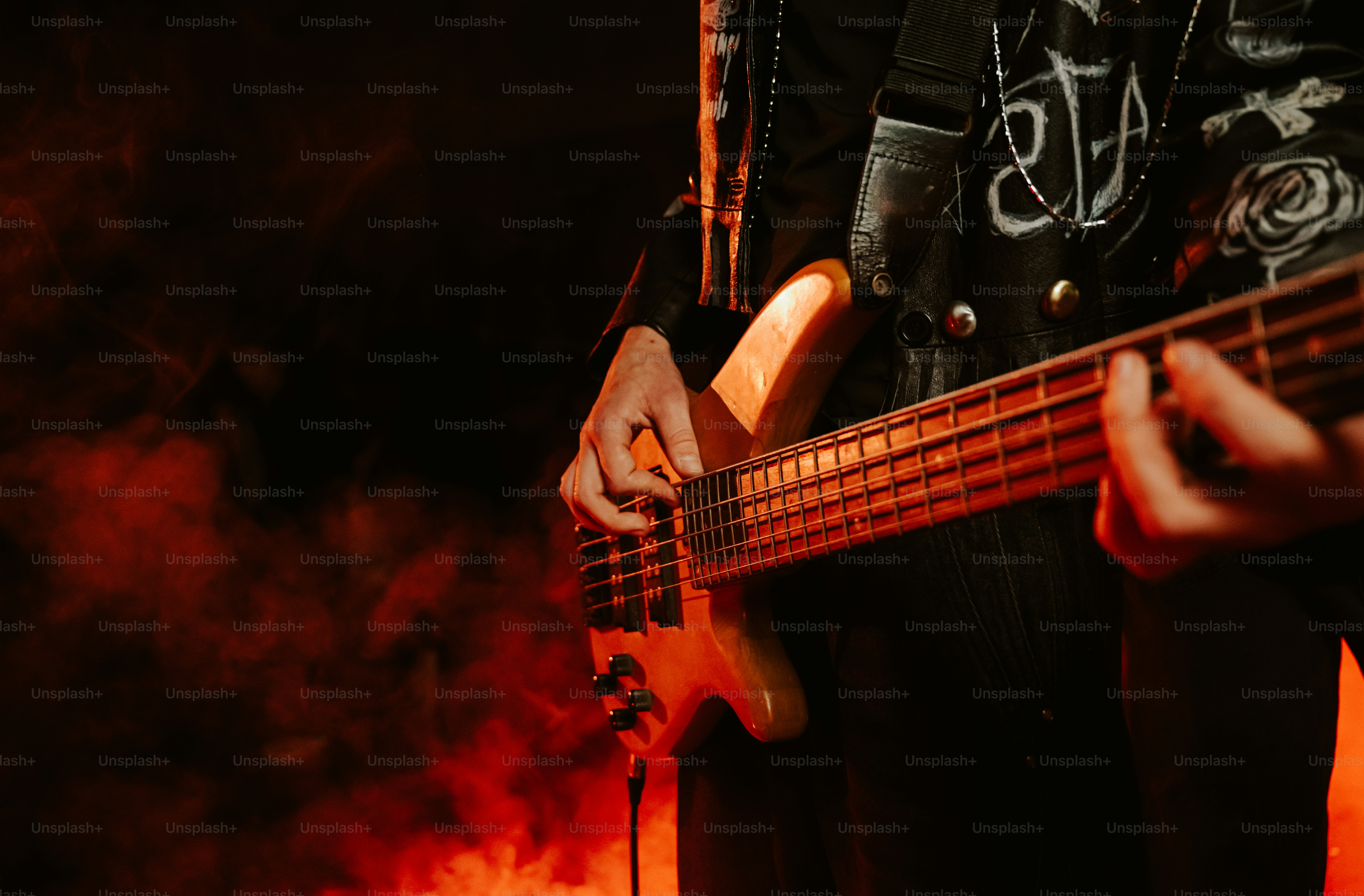 A person playing a bass guitar in a dark room with red smoke