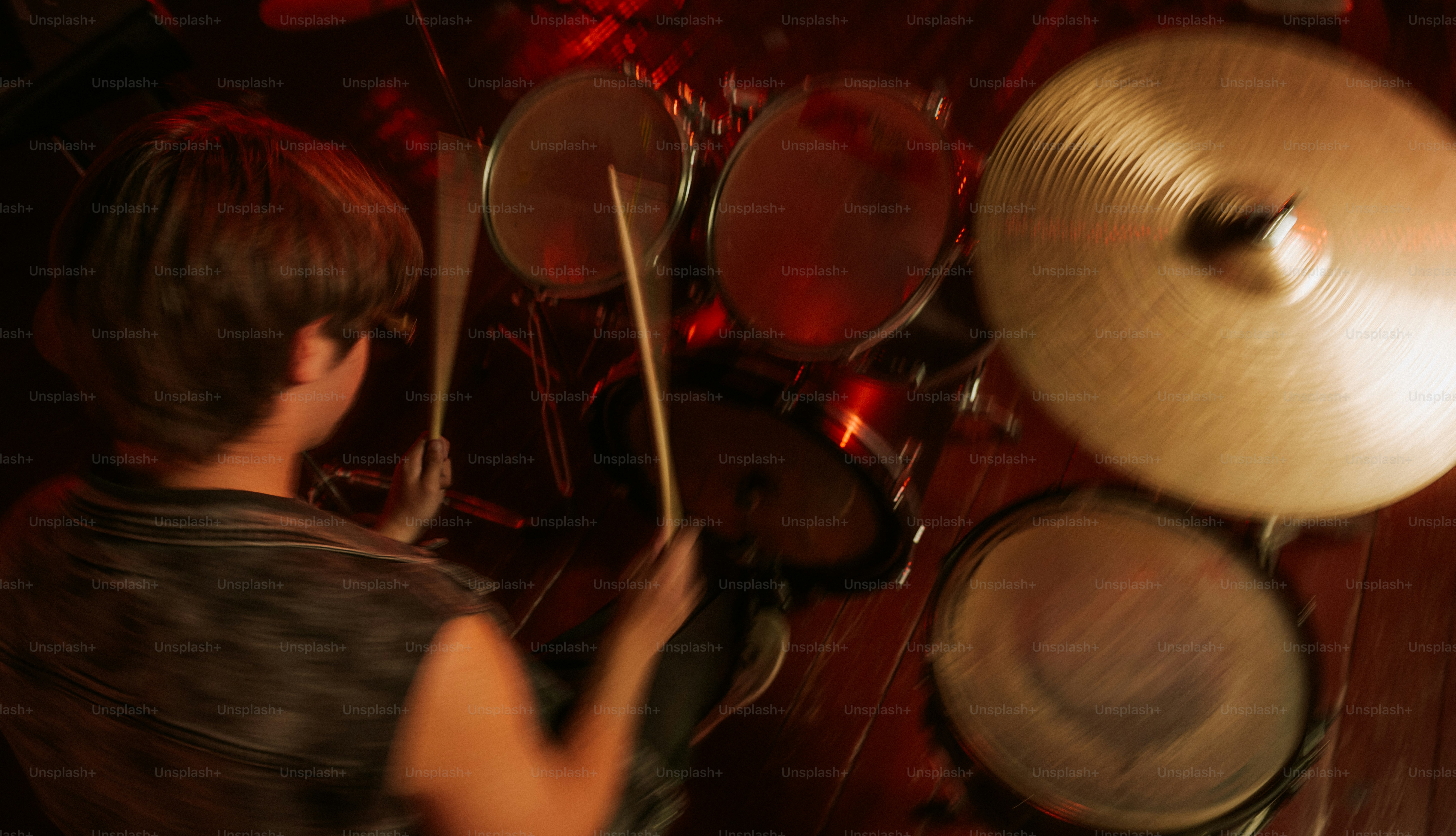 A drummer playing a drum kit with motion blur in a dimly lit room