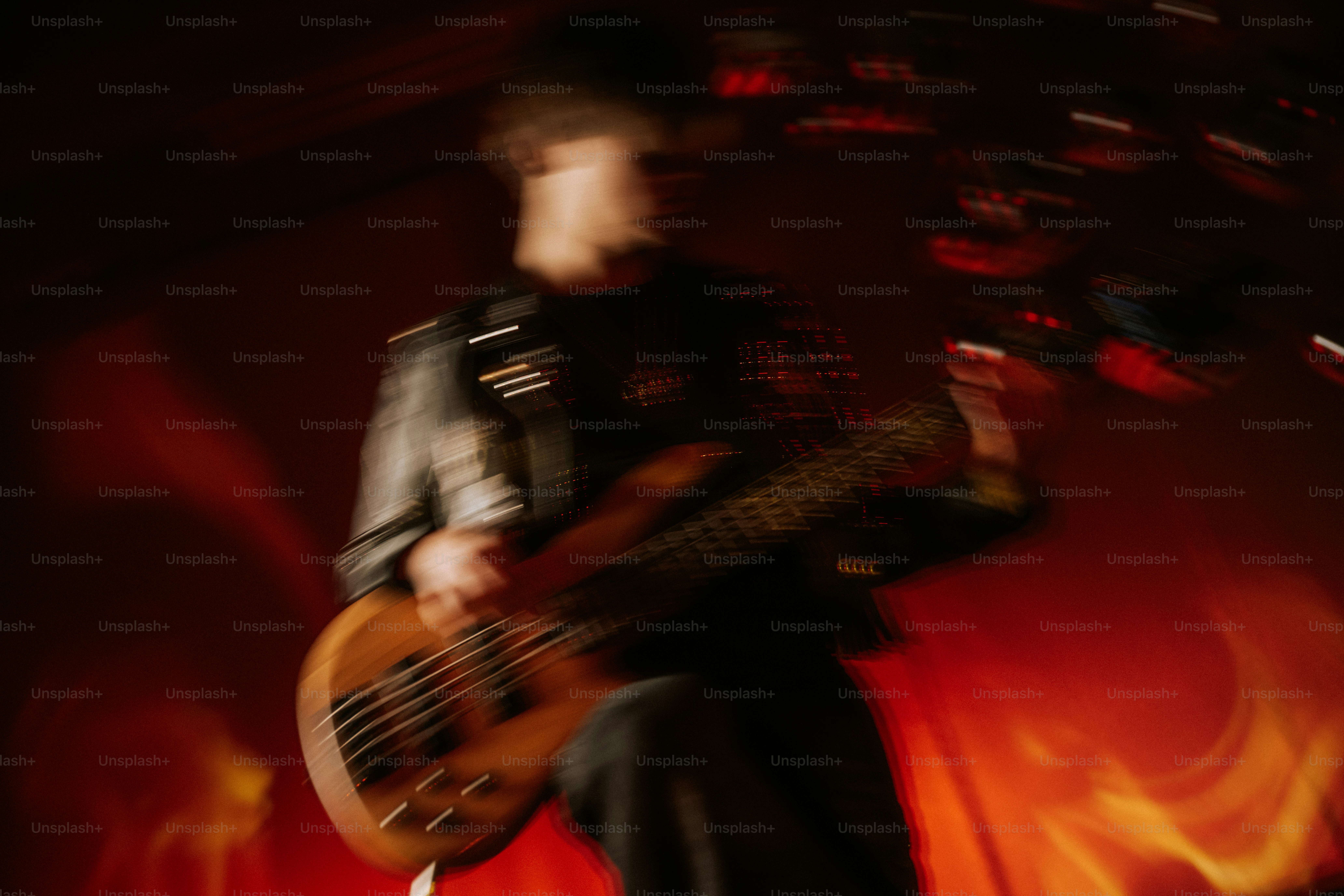 A person playing a bass guitar in a motion-blurred concert setting with red lighting