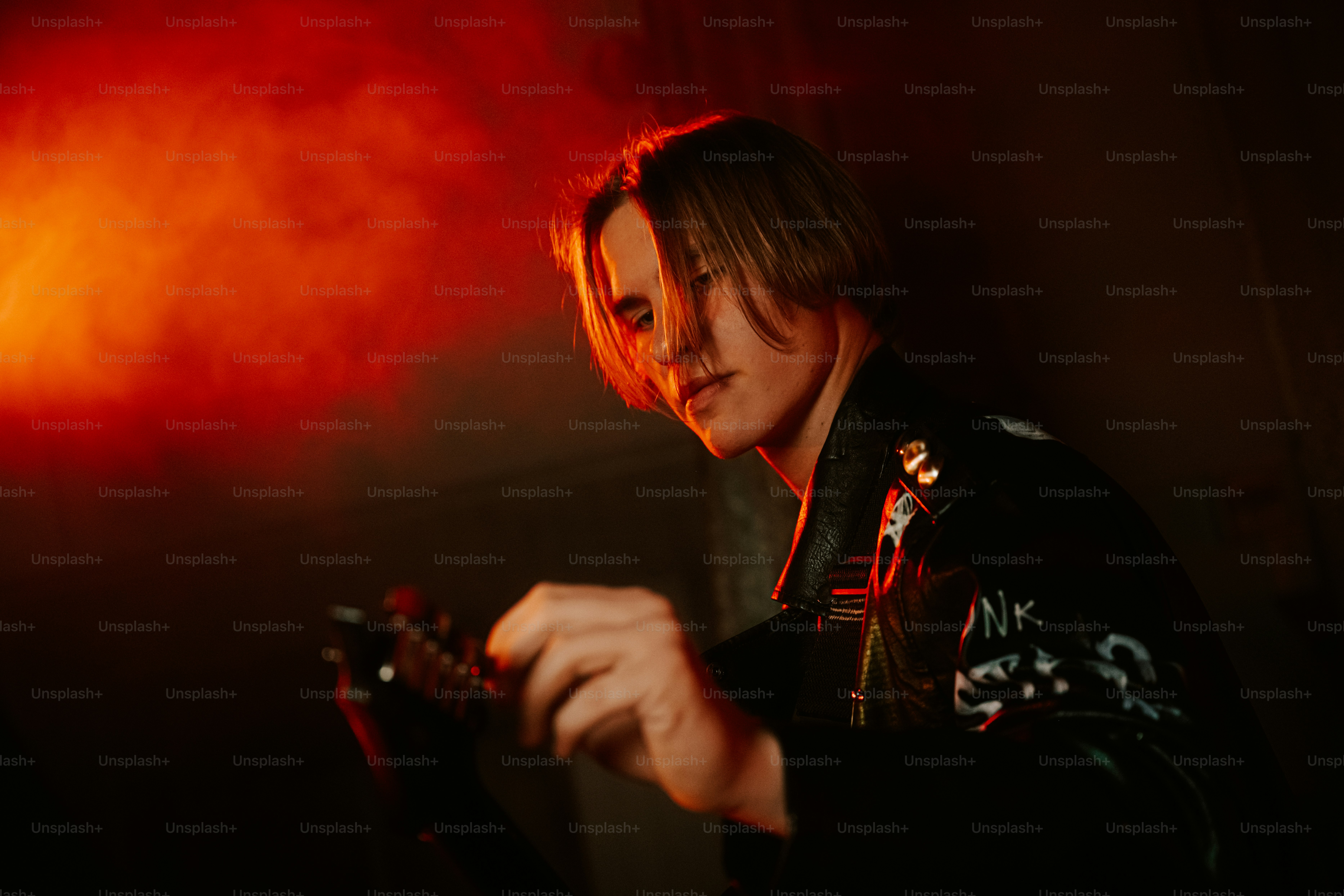 A person with blonde hair in a black leather jacket playing an electric guitar
