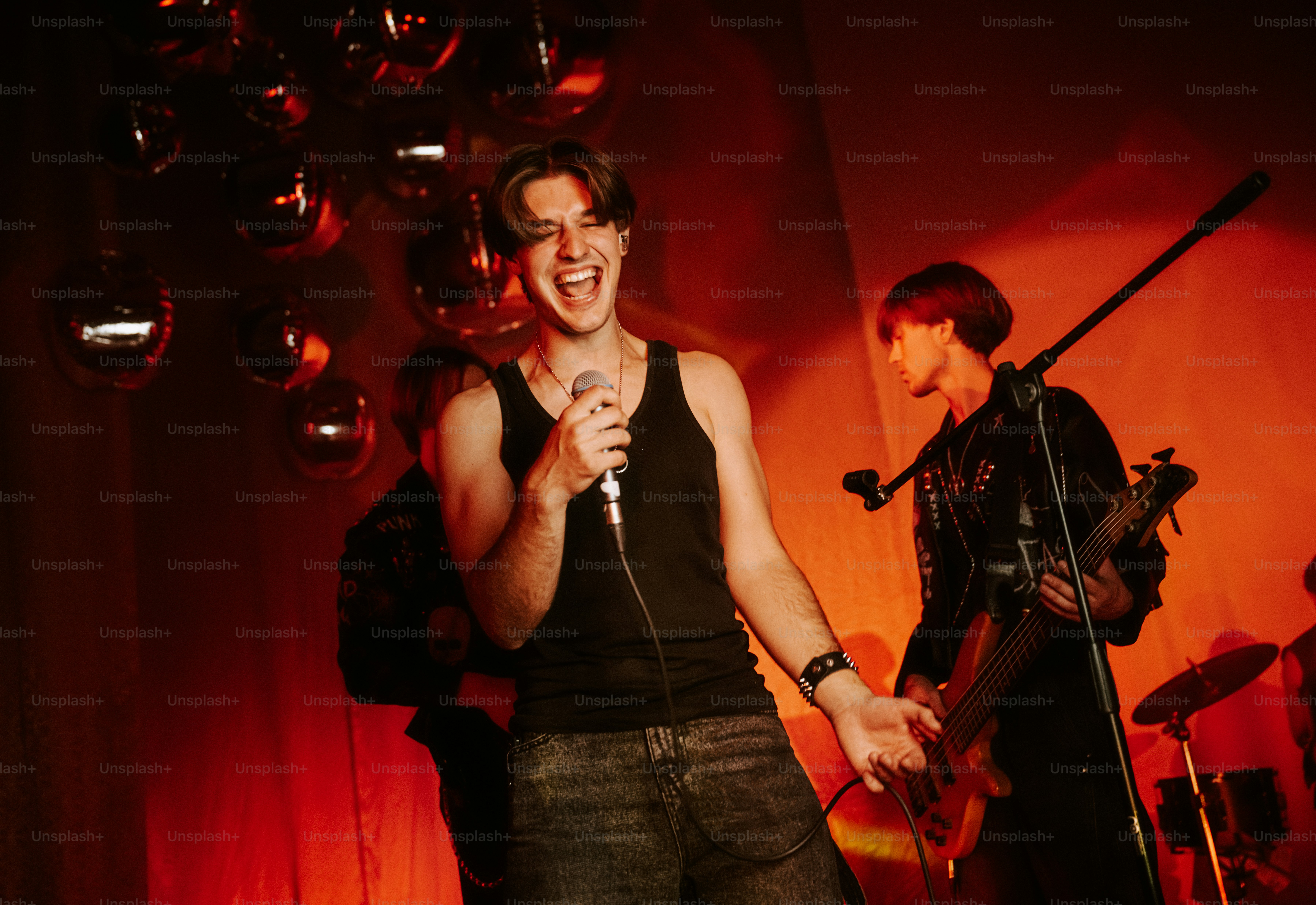 A man singing into a microphone on a stage with red lighting
