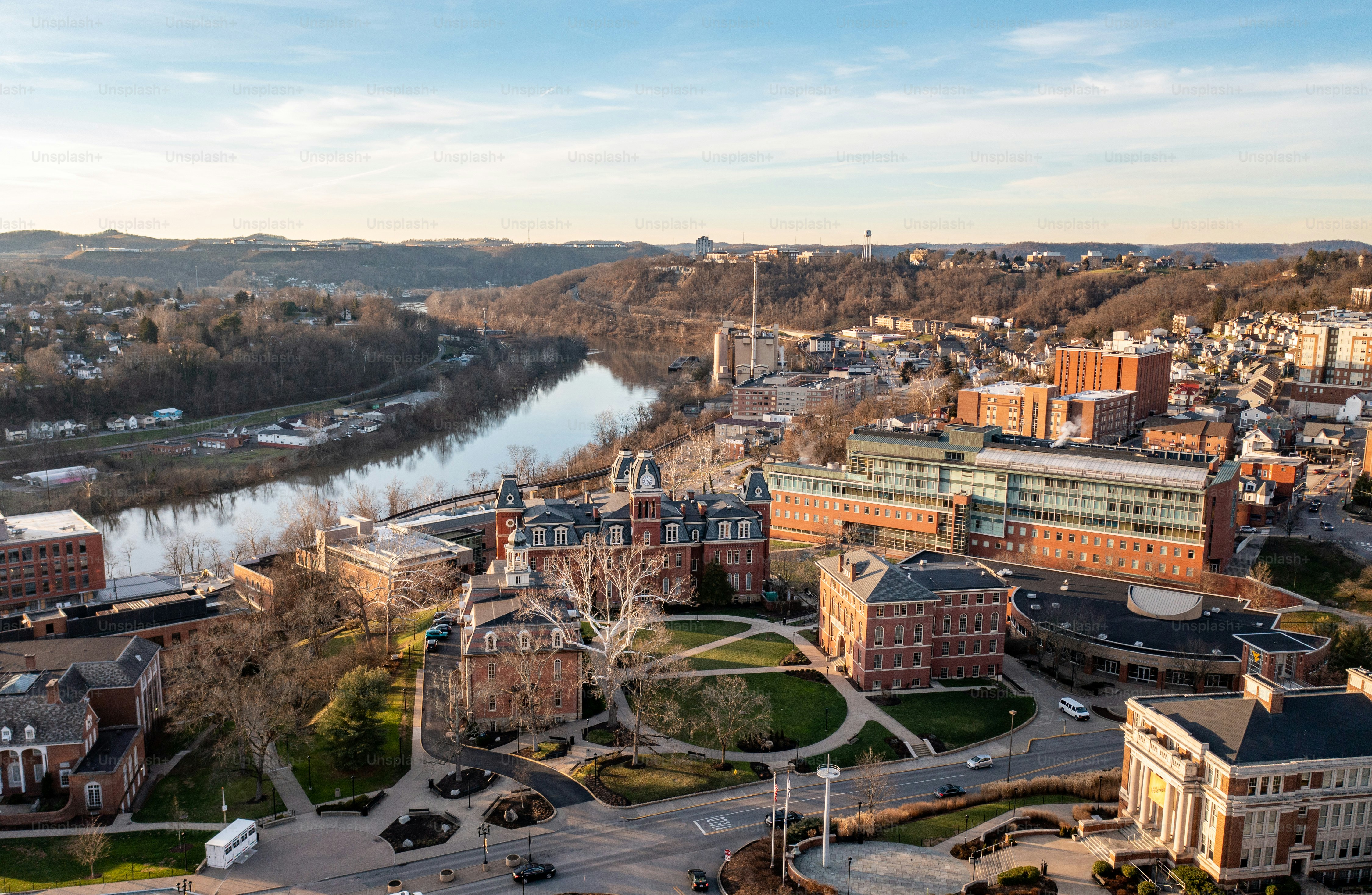 Plano panorámico aéreo con dron del campus del centro de WVU en Morgantown, Virginia Occidental, mostrando el río a lo lejos