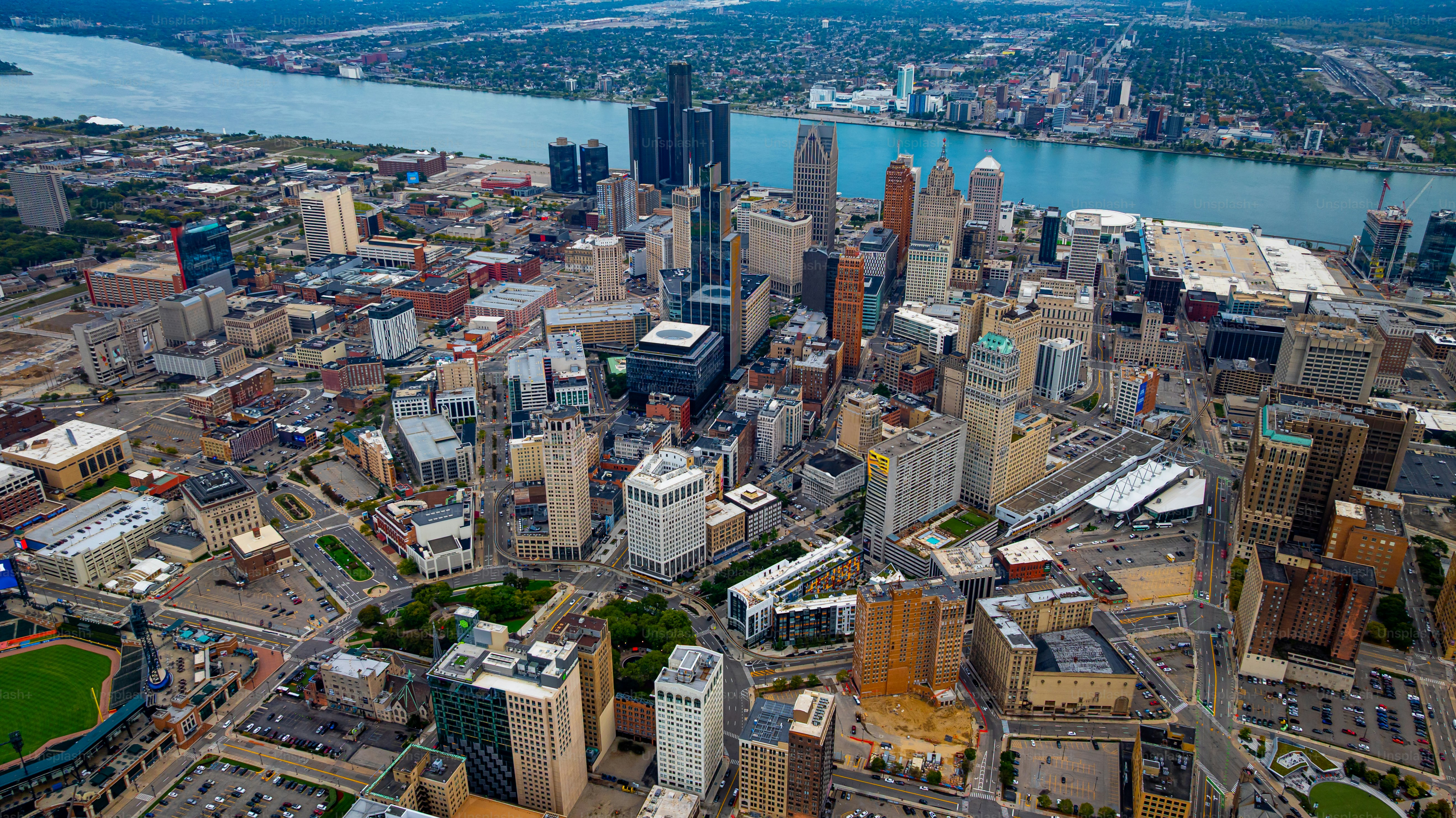 Detroit cityscape and riverfront. Drone photo of downtown Detroit skyline, the riverfront area, and city buildings under blue sky.