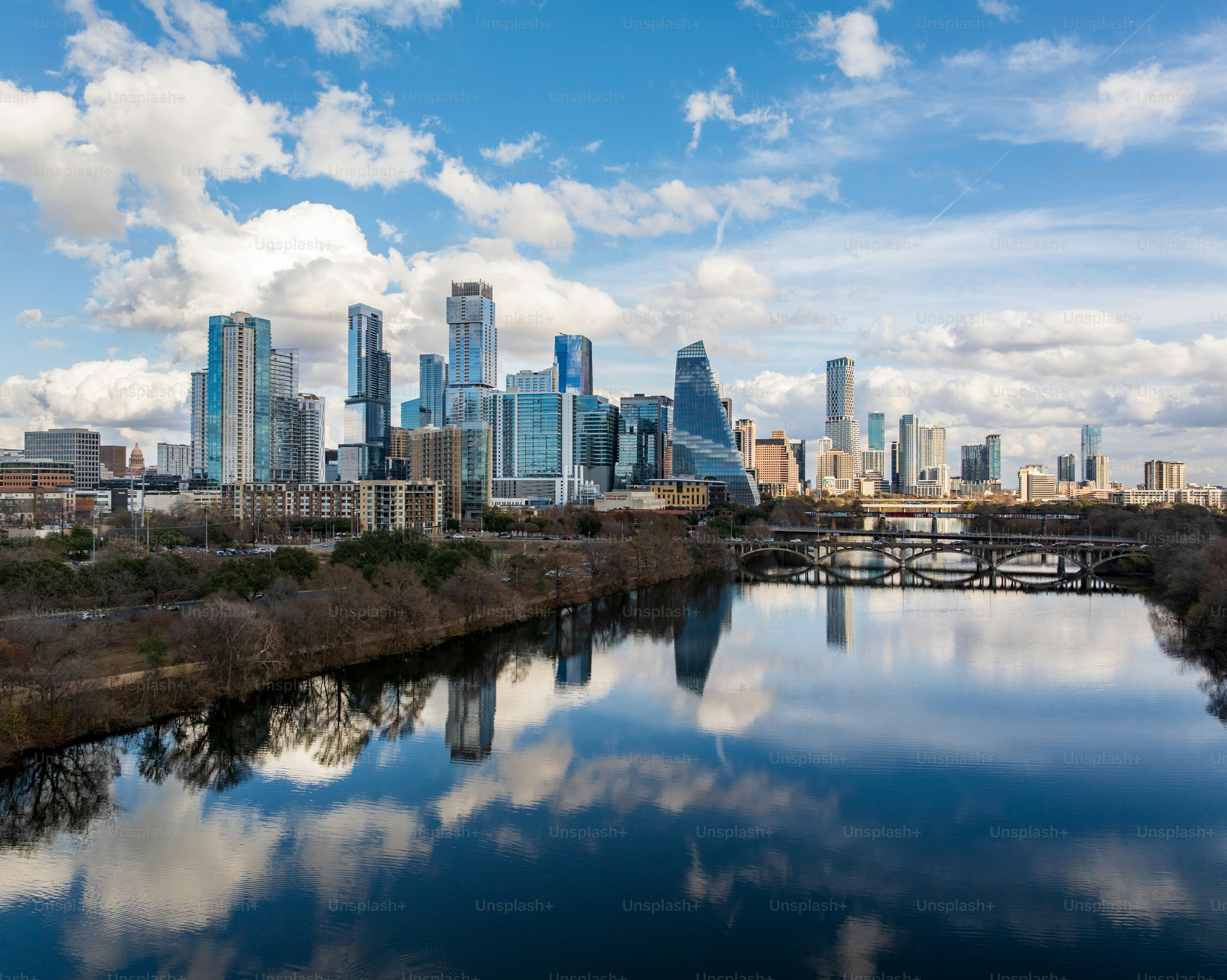 Clouds hover over the Austin skyline as buildings reflect on the calm waters of the Colorado river during late afternoon.
