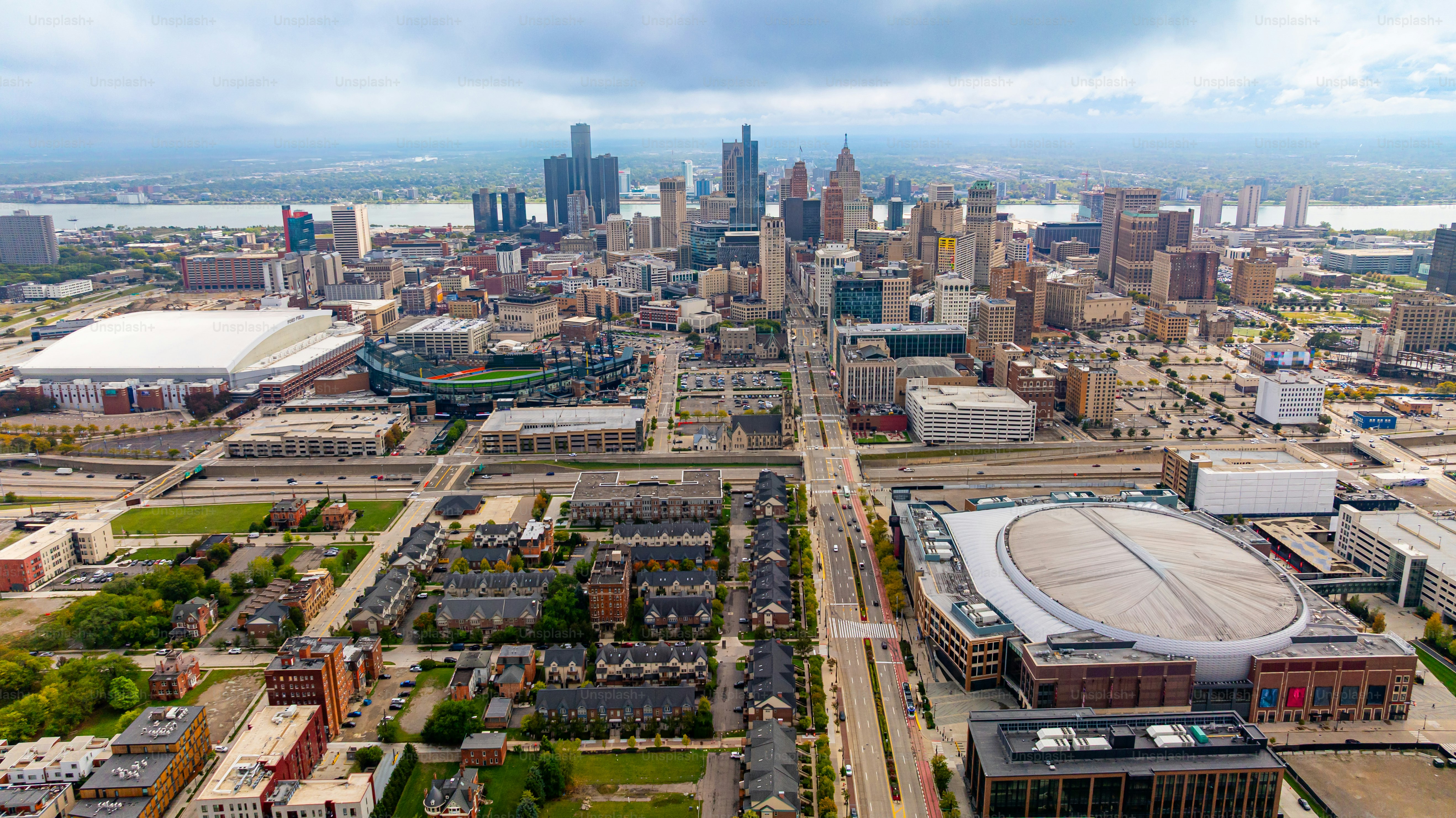 Aerial view of downtown Detroit skyline and stadiums. Downtown Detroit skyline with Comerica Park and Little Caesars Arena under cloudy sky.