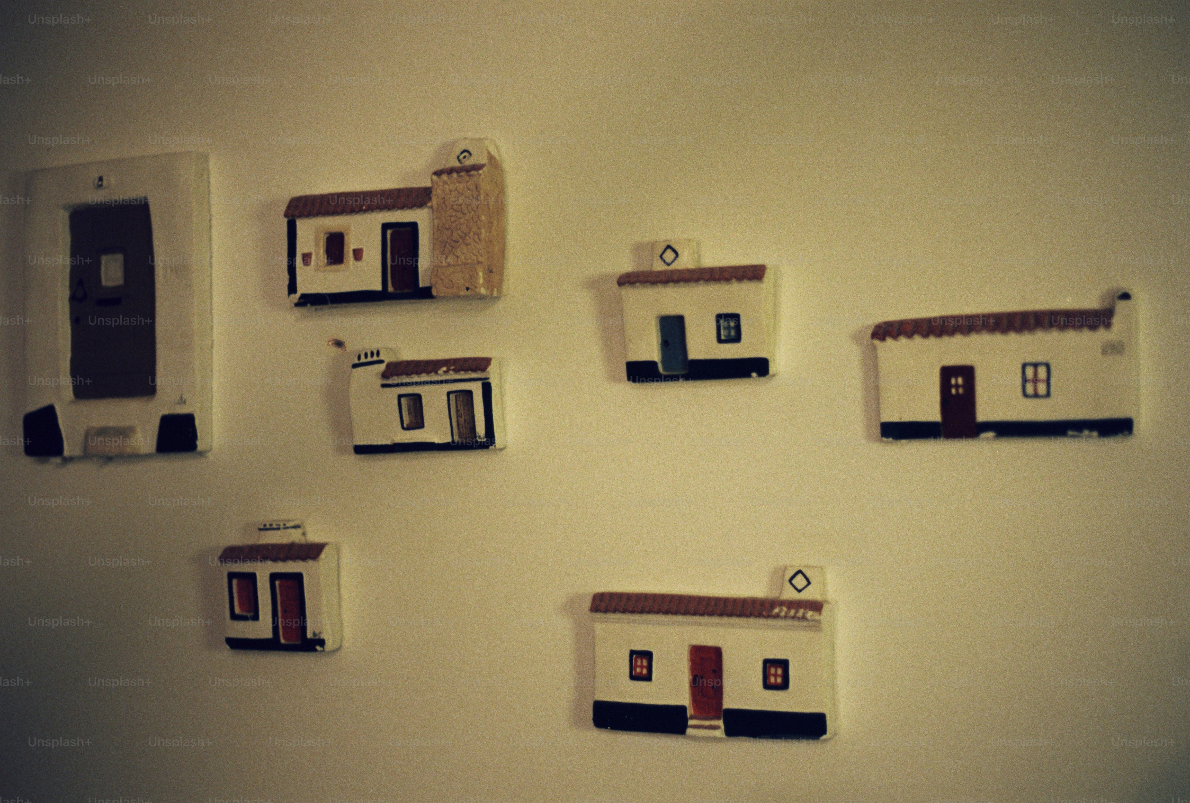 Small handmade ceramic house tiles with painted doors and roofs on a wall