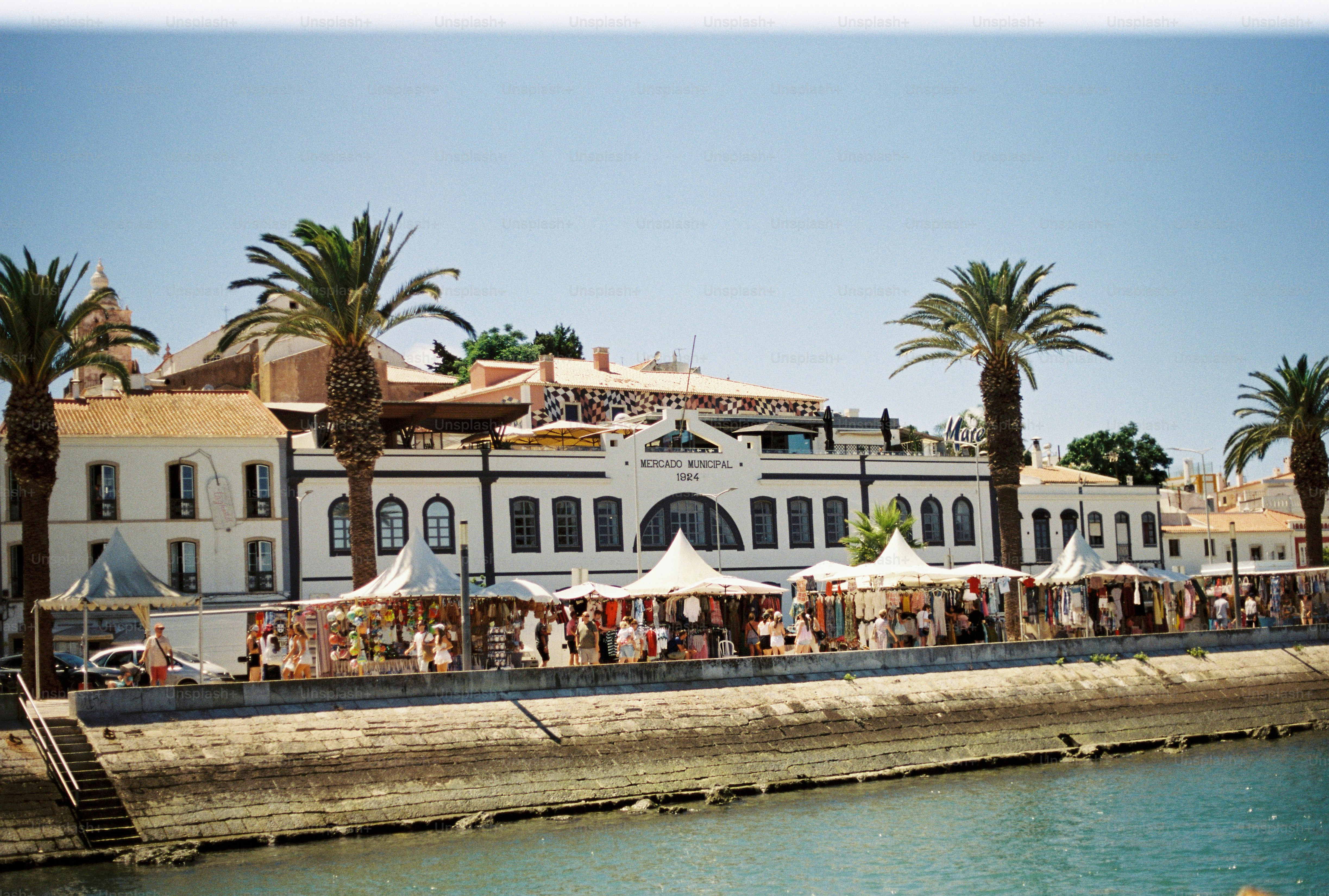 Puestos de mercado y palmeras frente al edificio municipal del Mercado en Lagos, Portugal