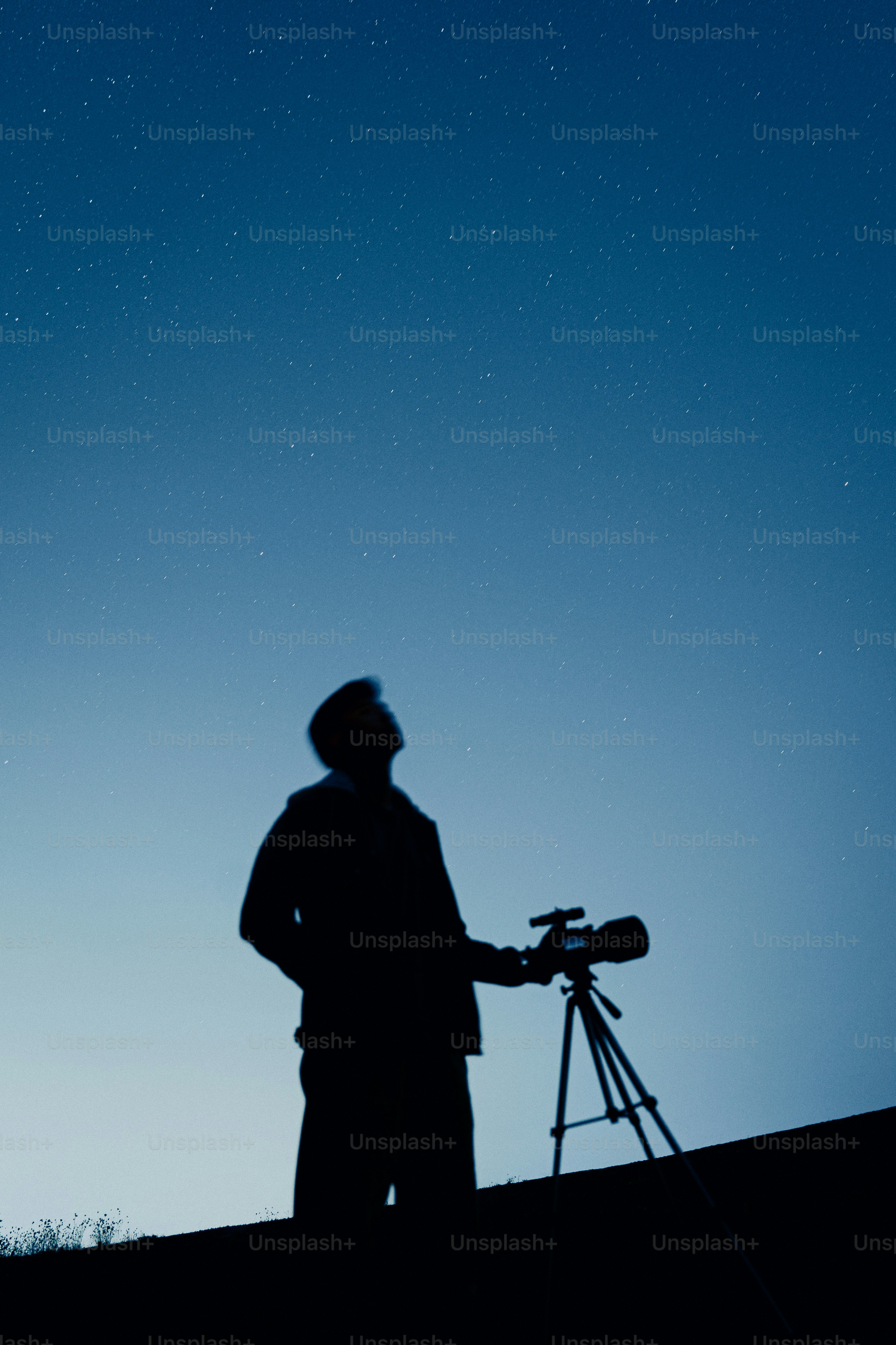 Una persona in silhouette con una macchina fotografica su un treppiede sotto un cielo stellato
