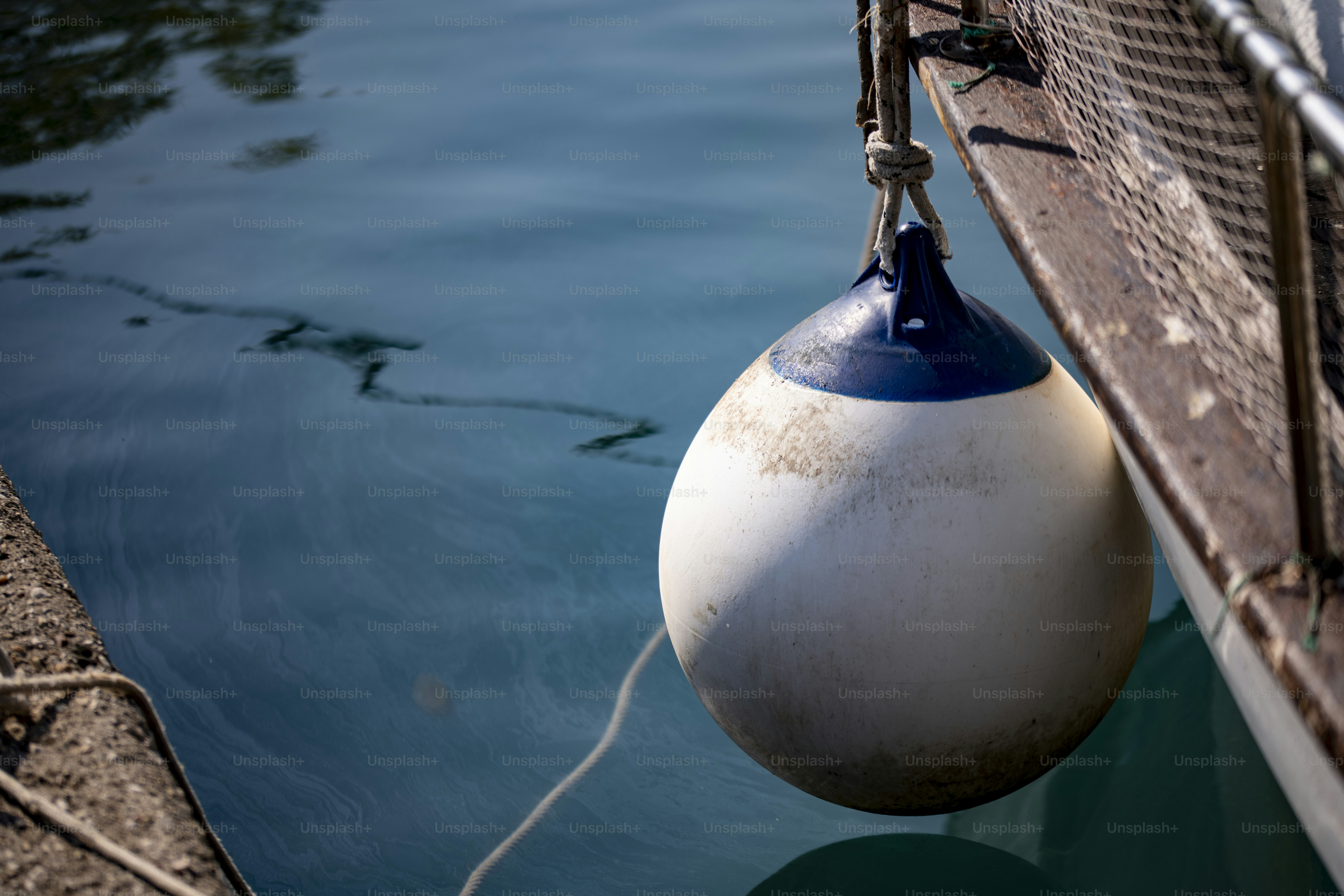 A white and blue boat fender hanging from a wooden boat hull