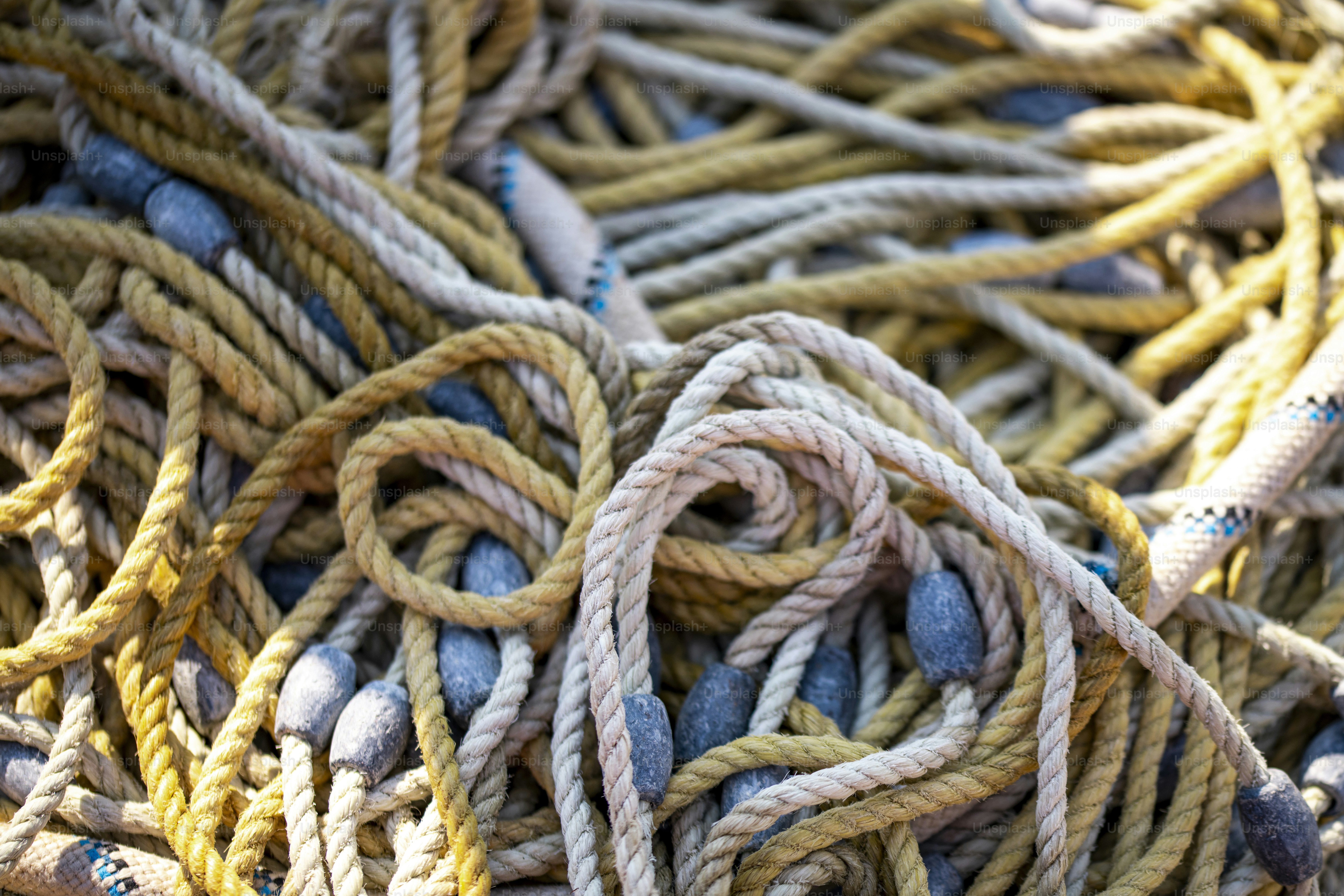 A tangled pile of yellow and white nautical ropes with grey lead weights