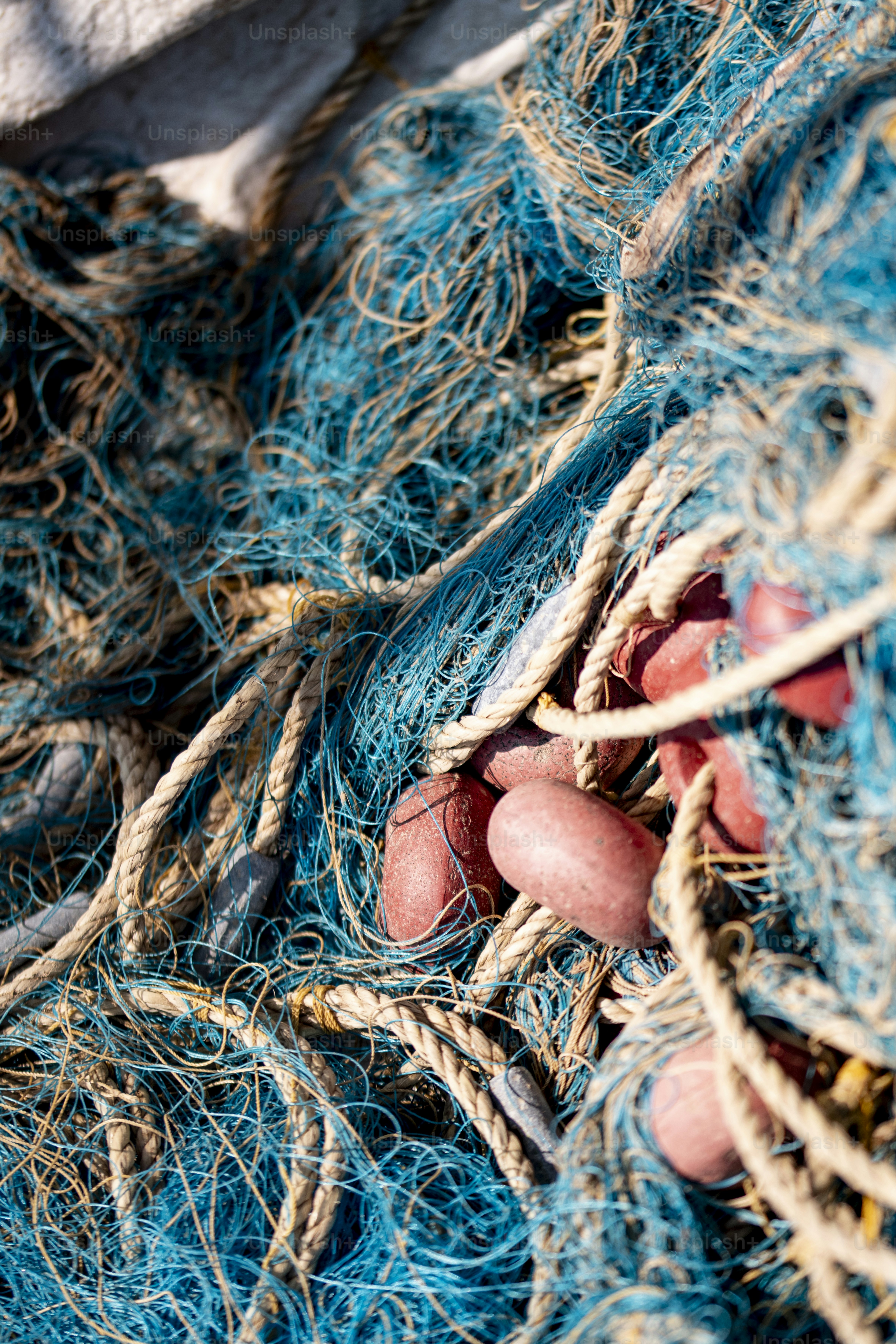 Blue fishing nets tangled with red plastic floats on a wooden deck