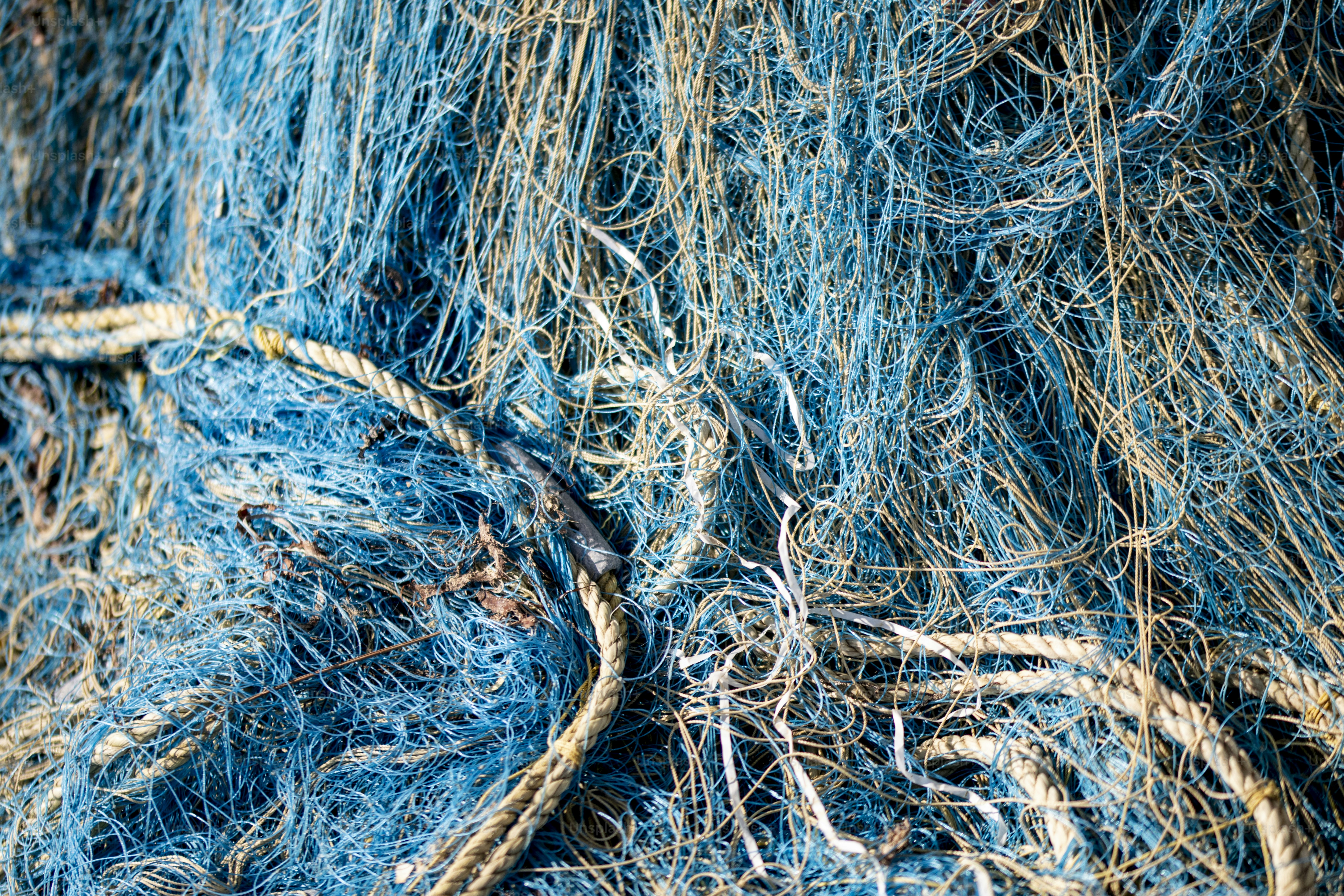 A tangled pile of blue nylon fishing nets and thick white rope