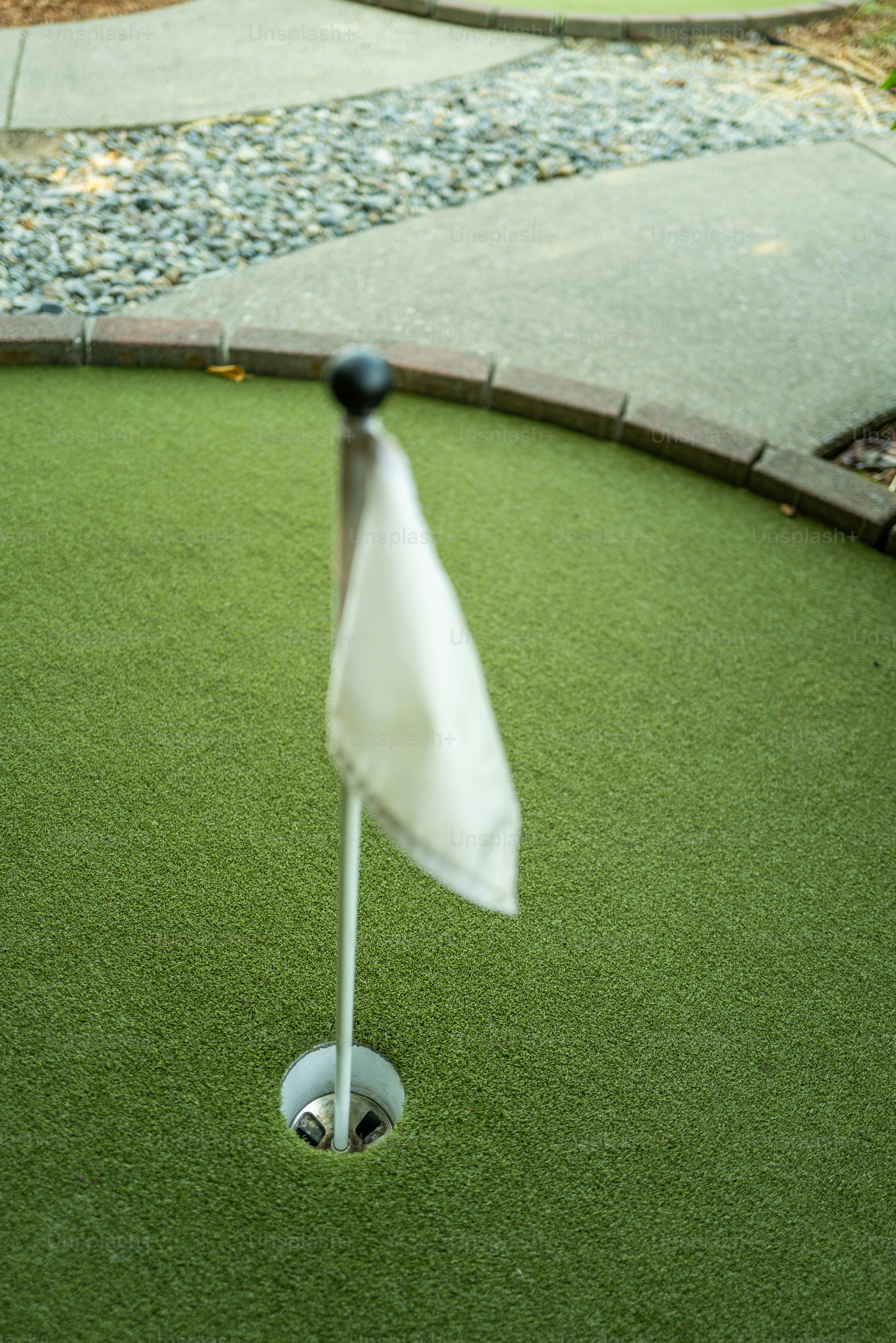 Eine weiße Fahne in einem Loch auf einem grünen Minigolfplatz