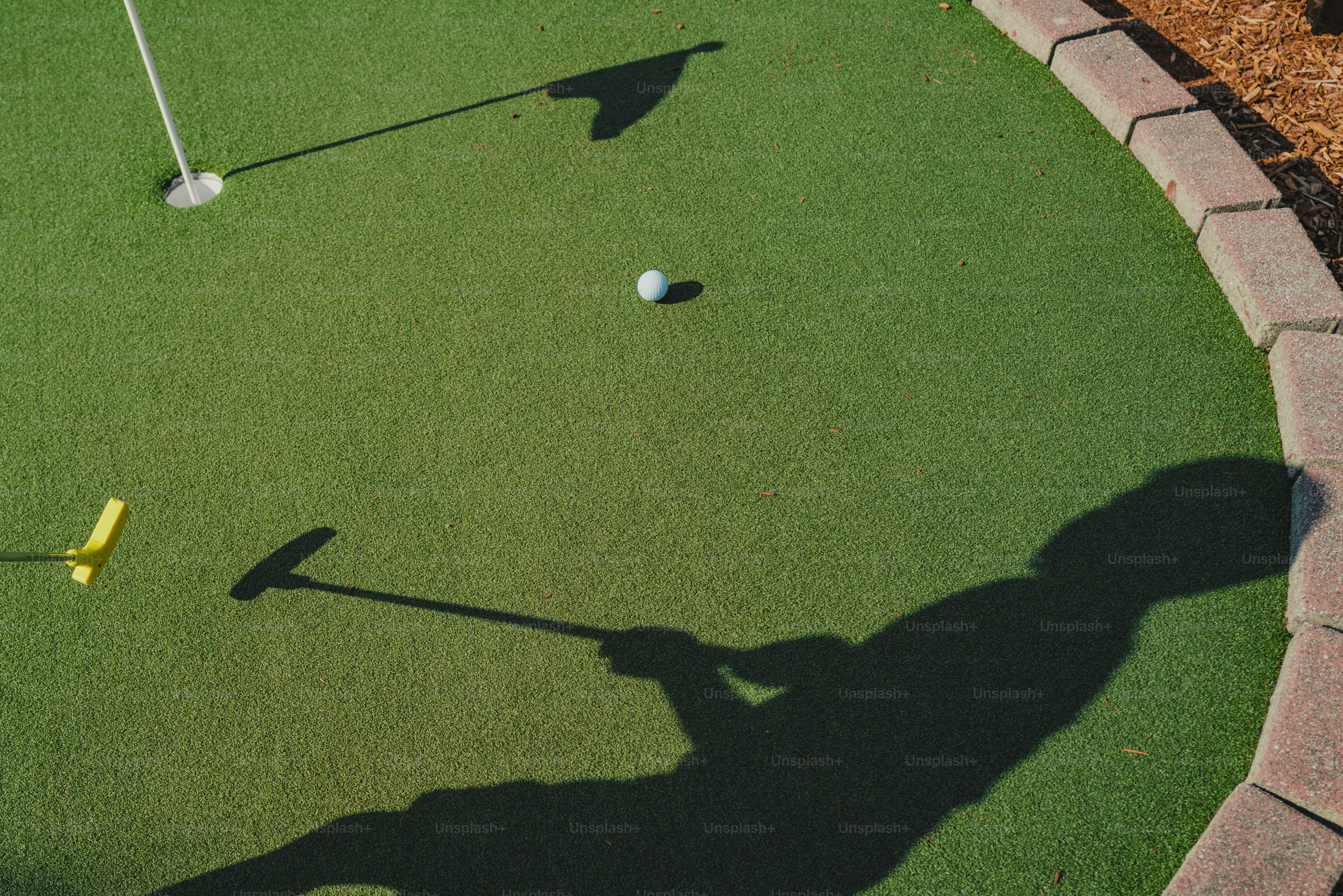 Ein Golfball auf einem Grün mit dem Schatten einer Person