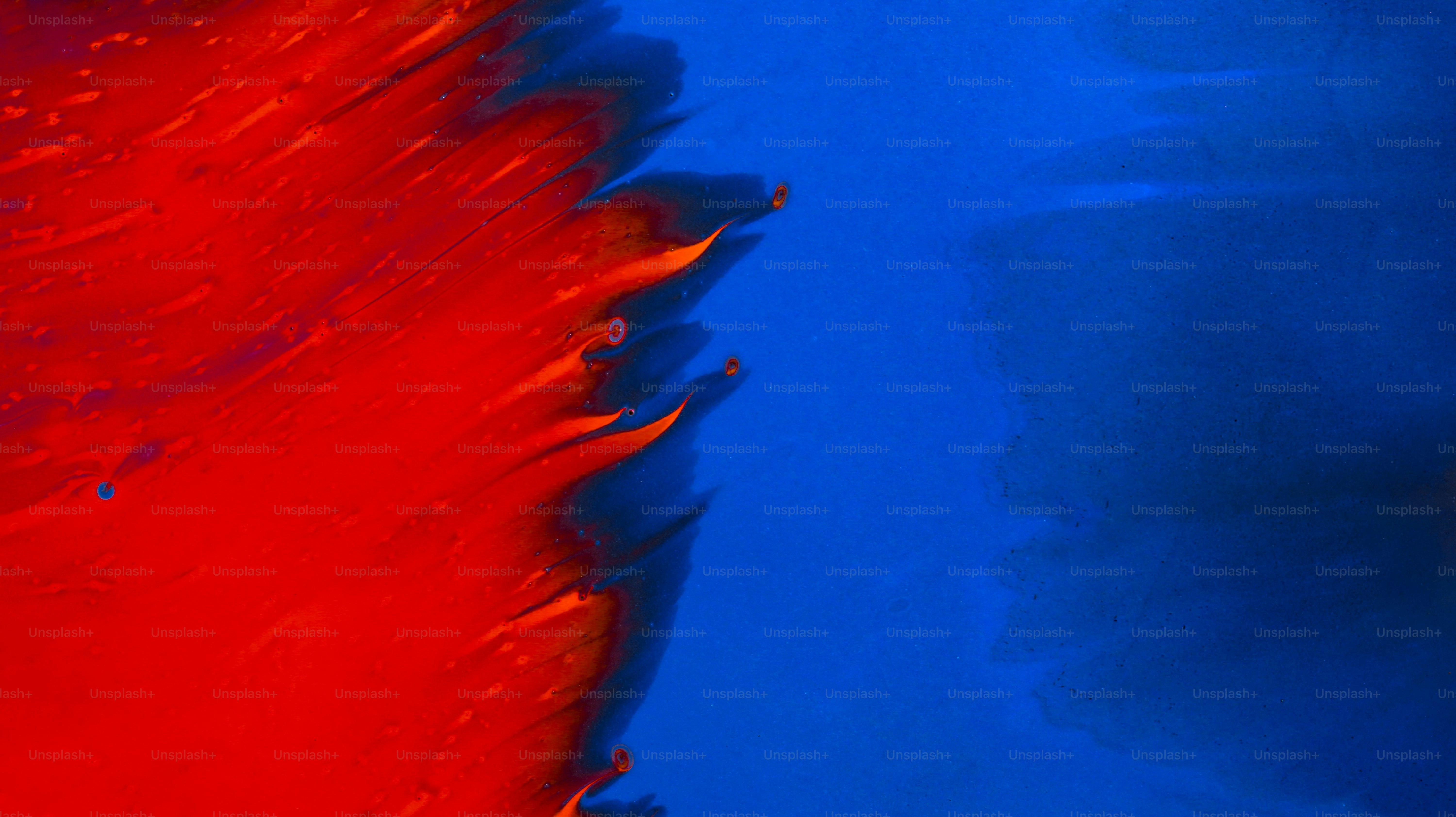 Vibrant red and orange liquid swirling into a deep blue background