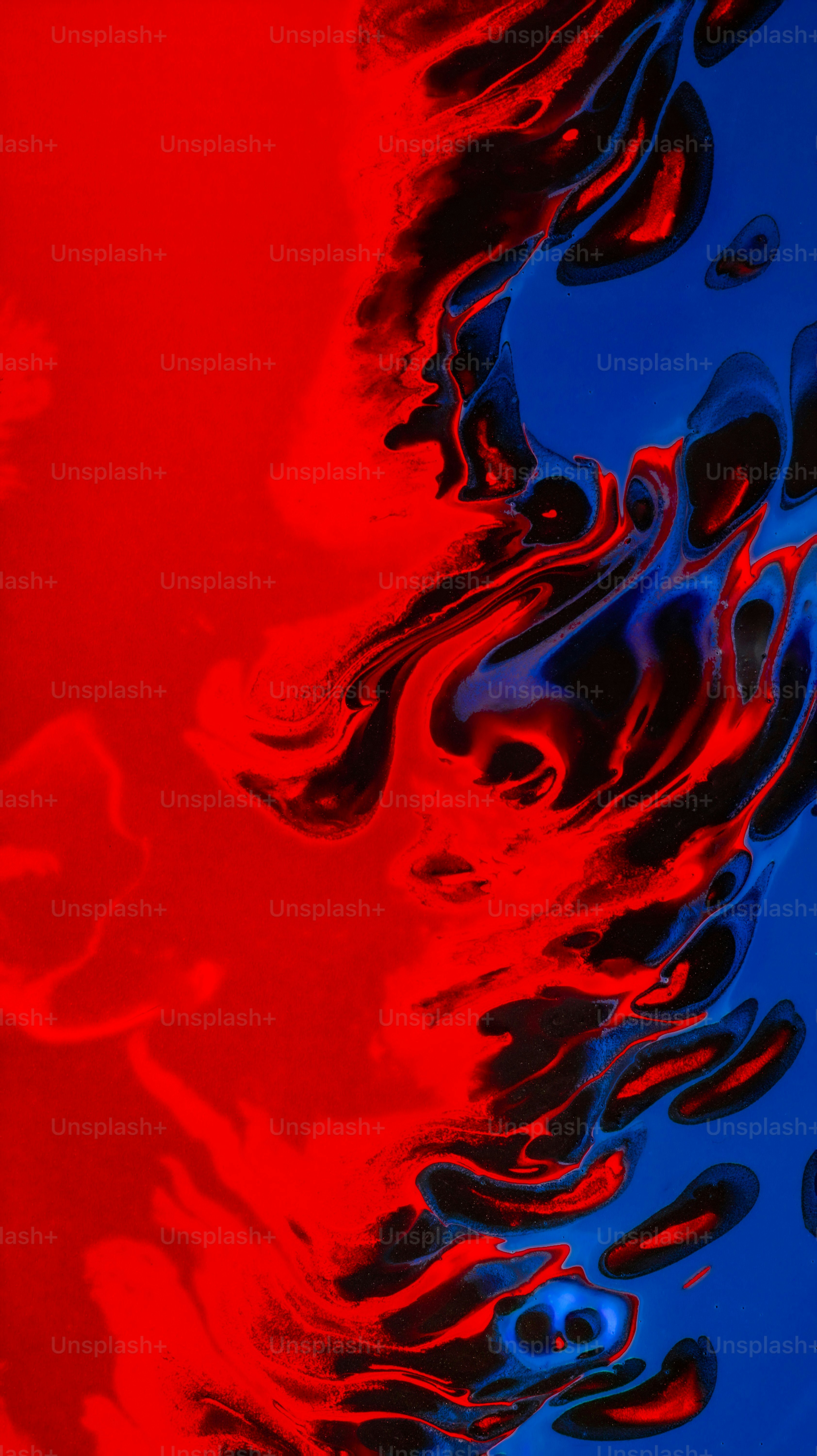Swirling patterns of vibrant red and deep blue liquid paint