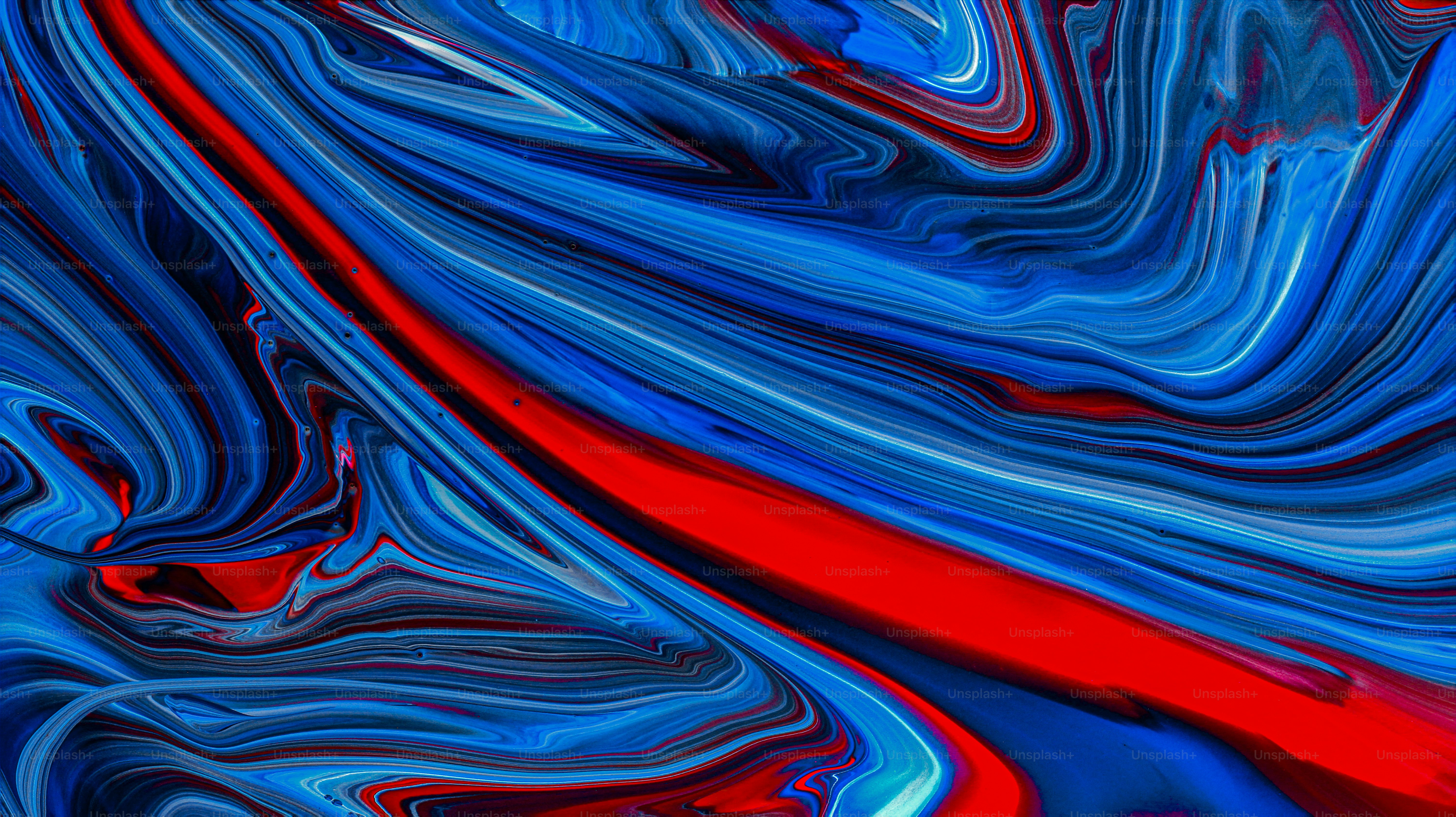 Swirling patterns of vibrant blue, red, and black liquid paint