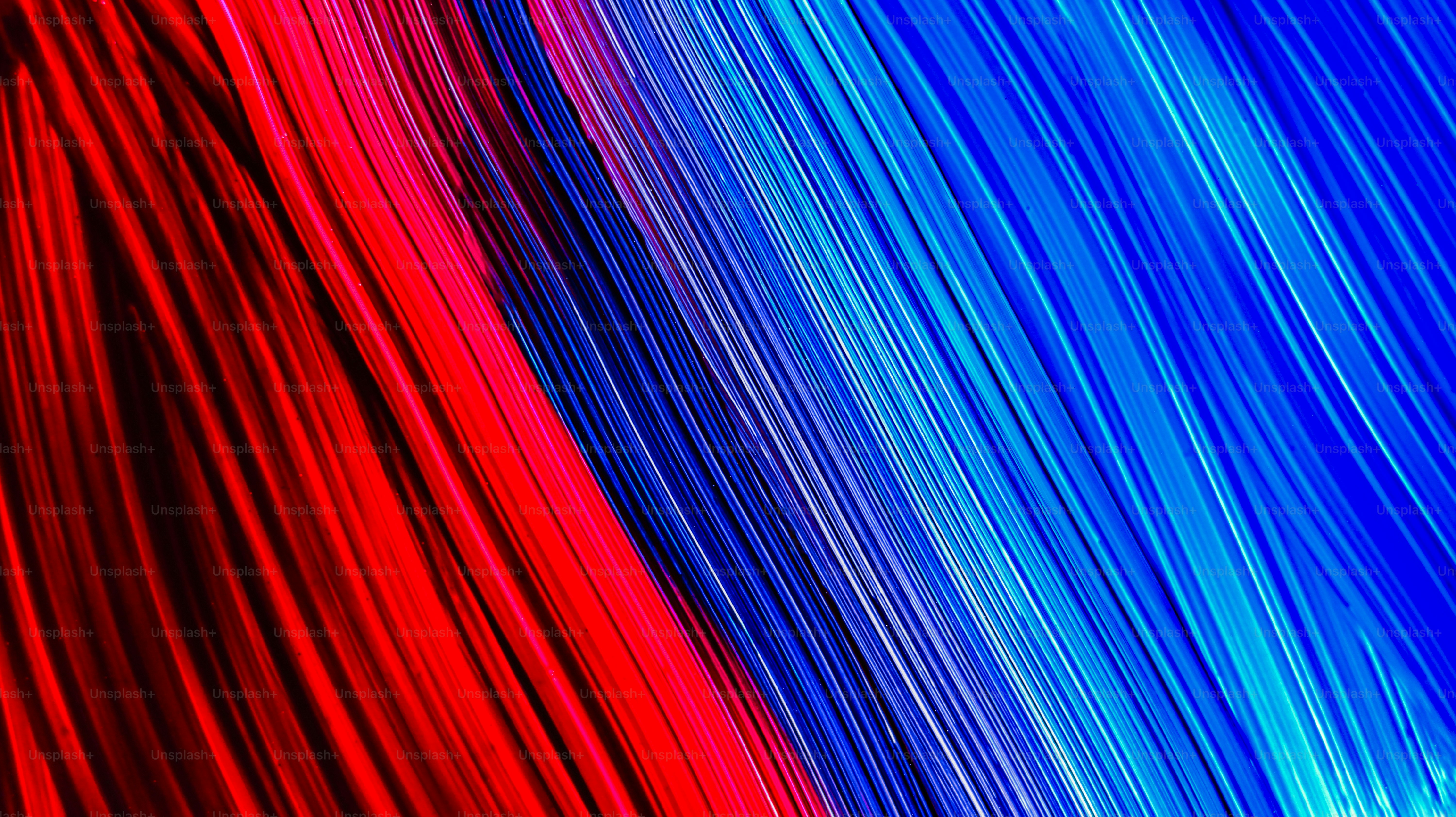 Diagonal streaks of vibrant red and blue light against a dark background