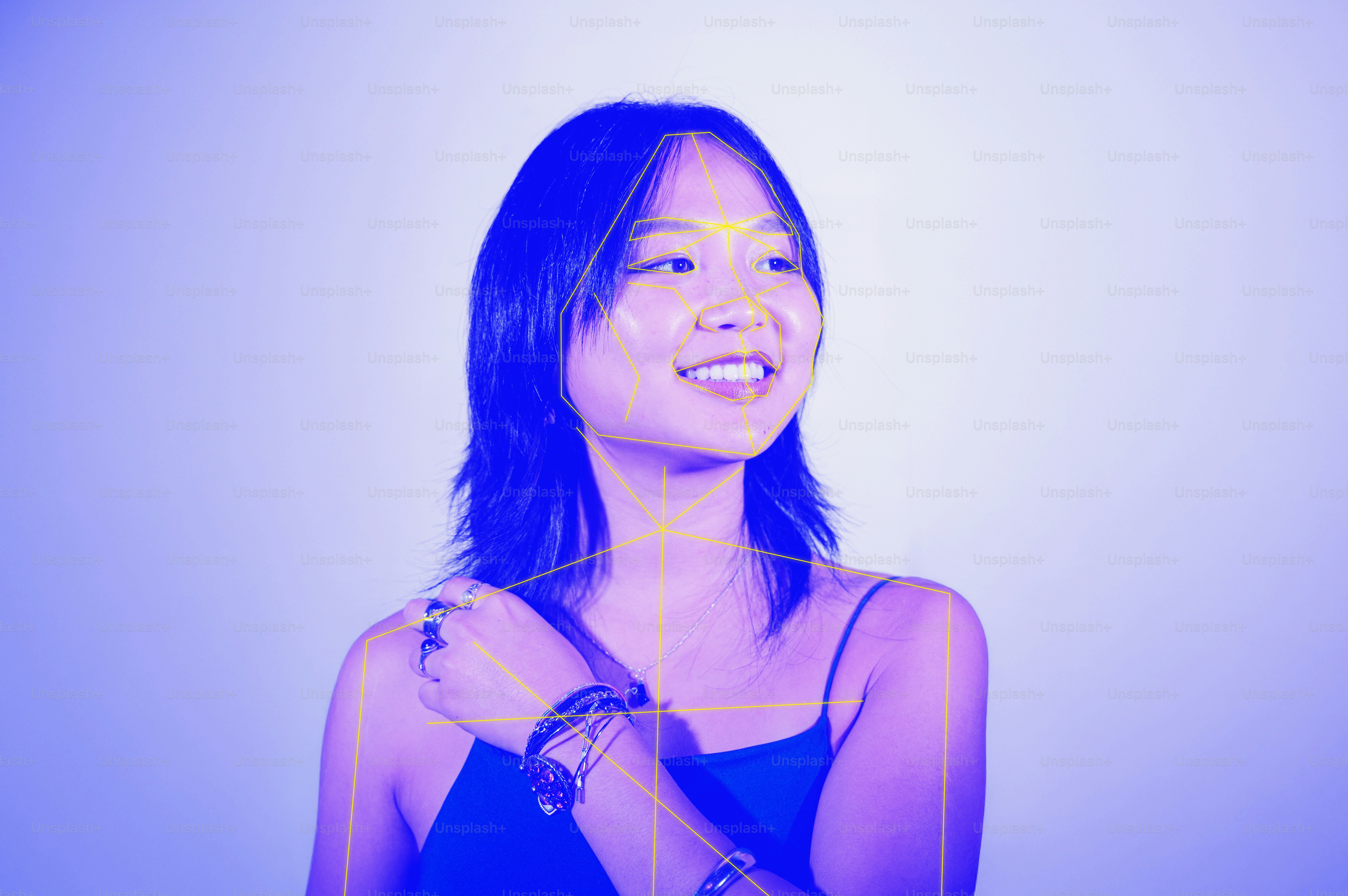 A woman with a yellow facial tracking mesh overlay in blue light