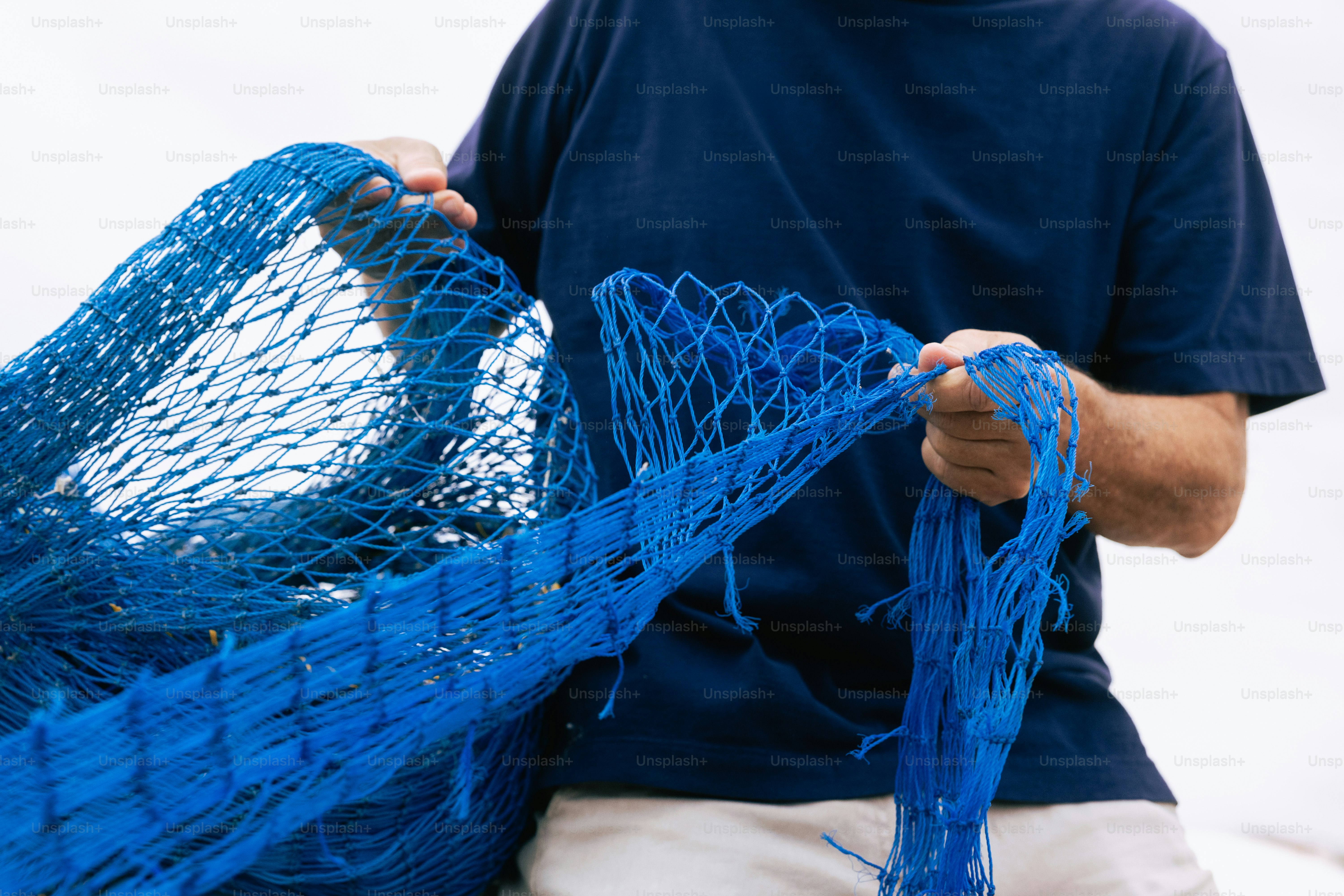 A person in a dark blue t-shirt holding a blue fishing net