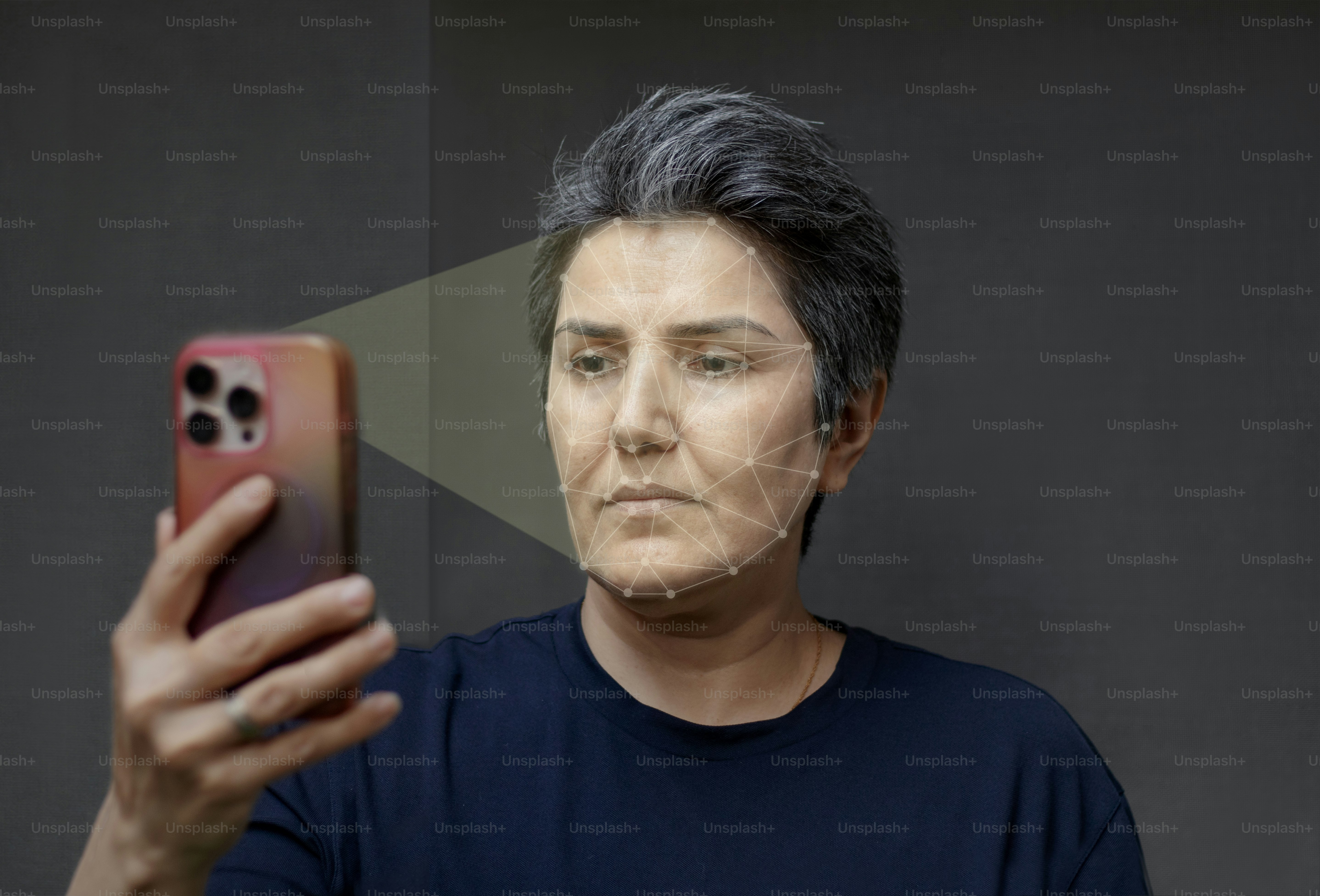 A person with short grey hair using a smartphone for facial recognition scanning