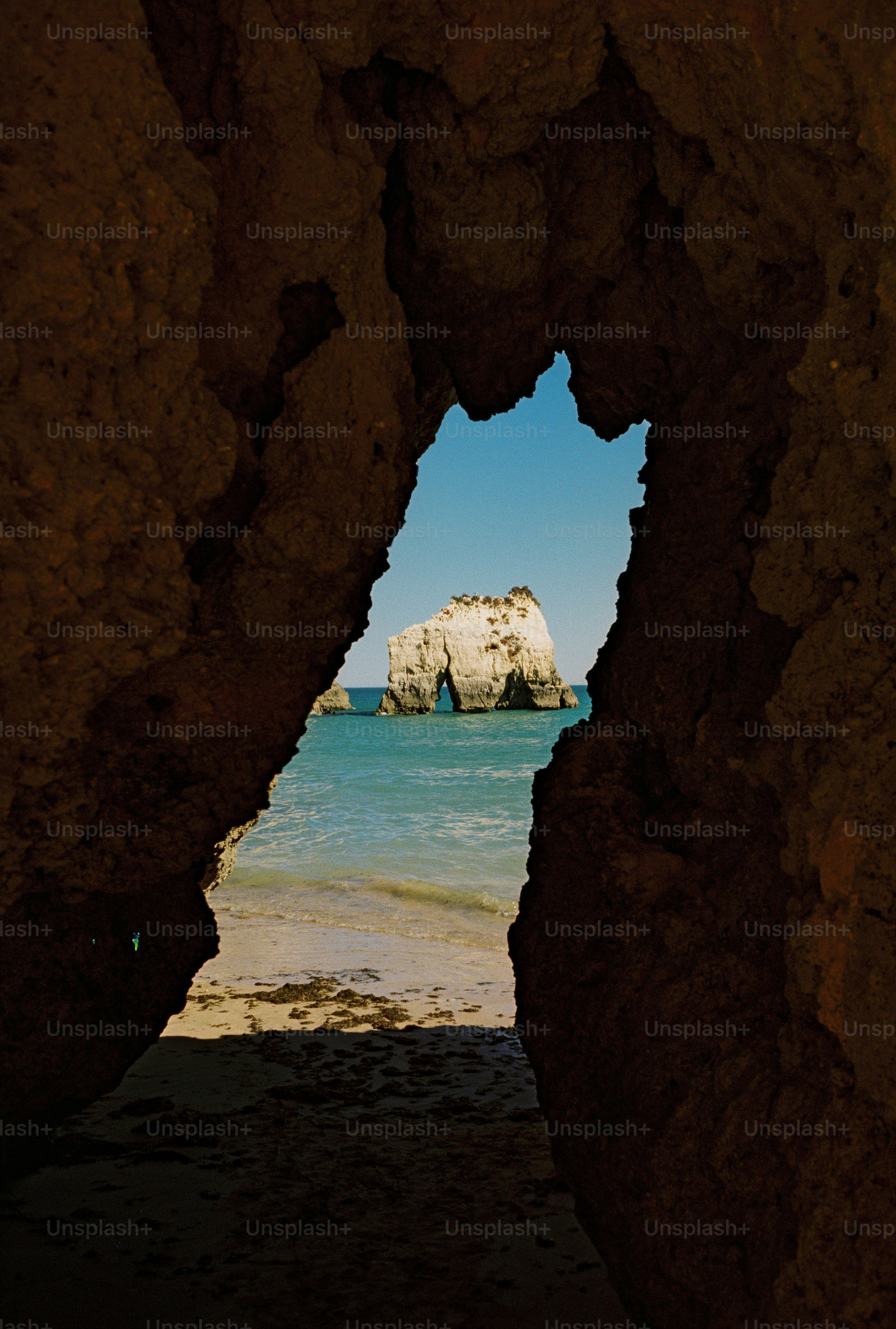 Un pimiento marino de piedra caliza enmarcado por una oscura abertura de cueva en Alvor, Portugal