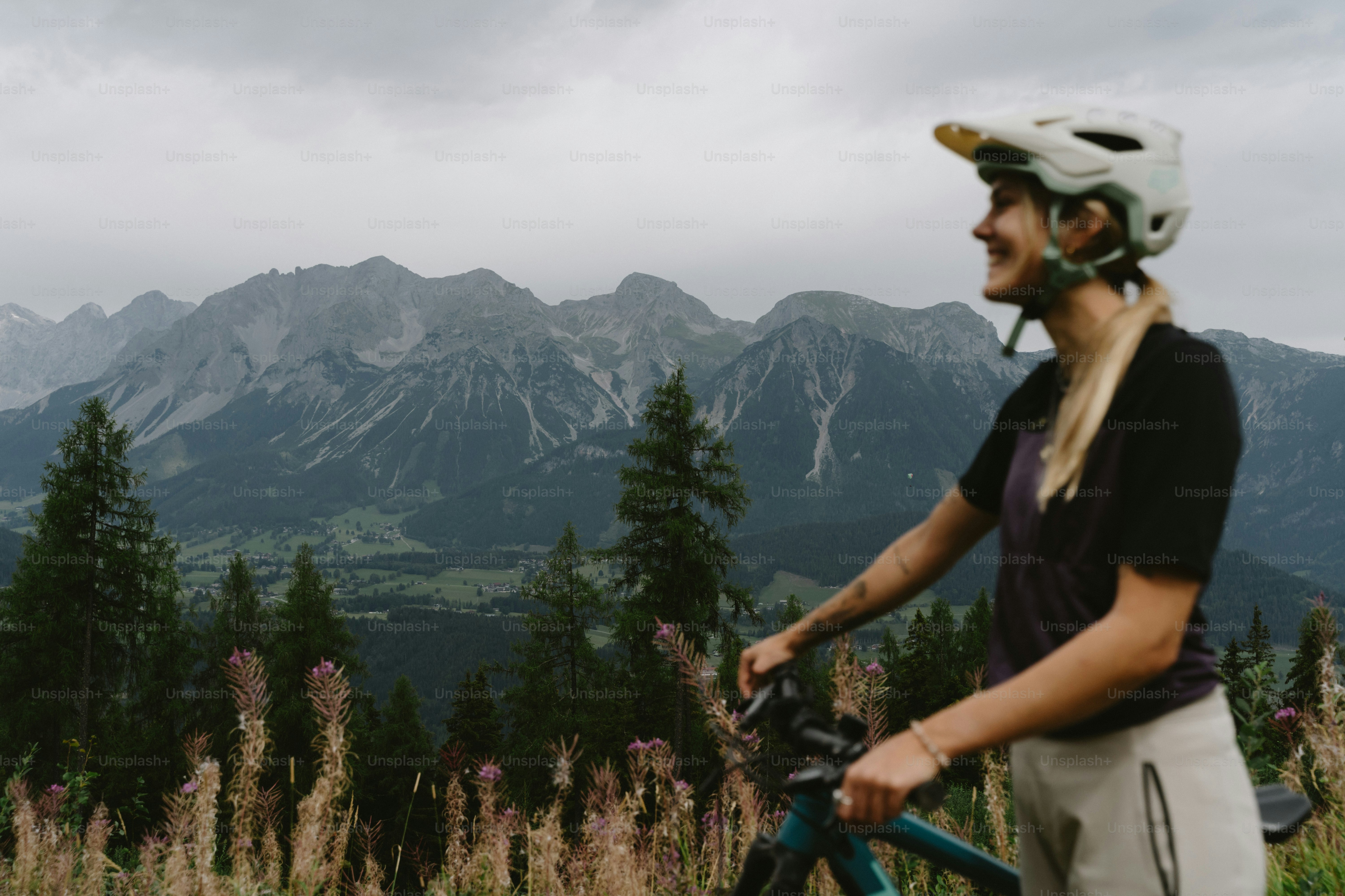 A woman in a helmet with a mountain bike overlooking a green valley
