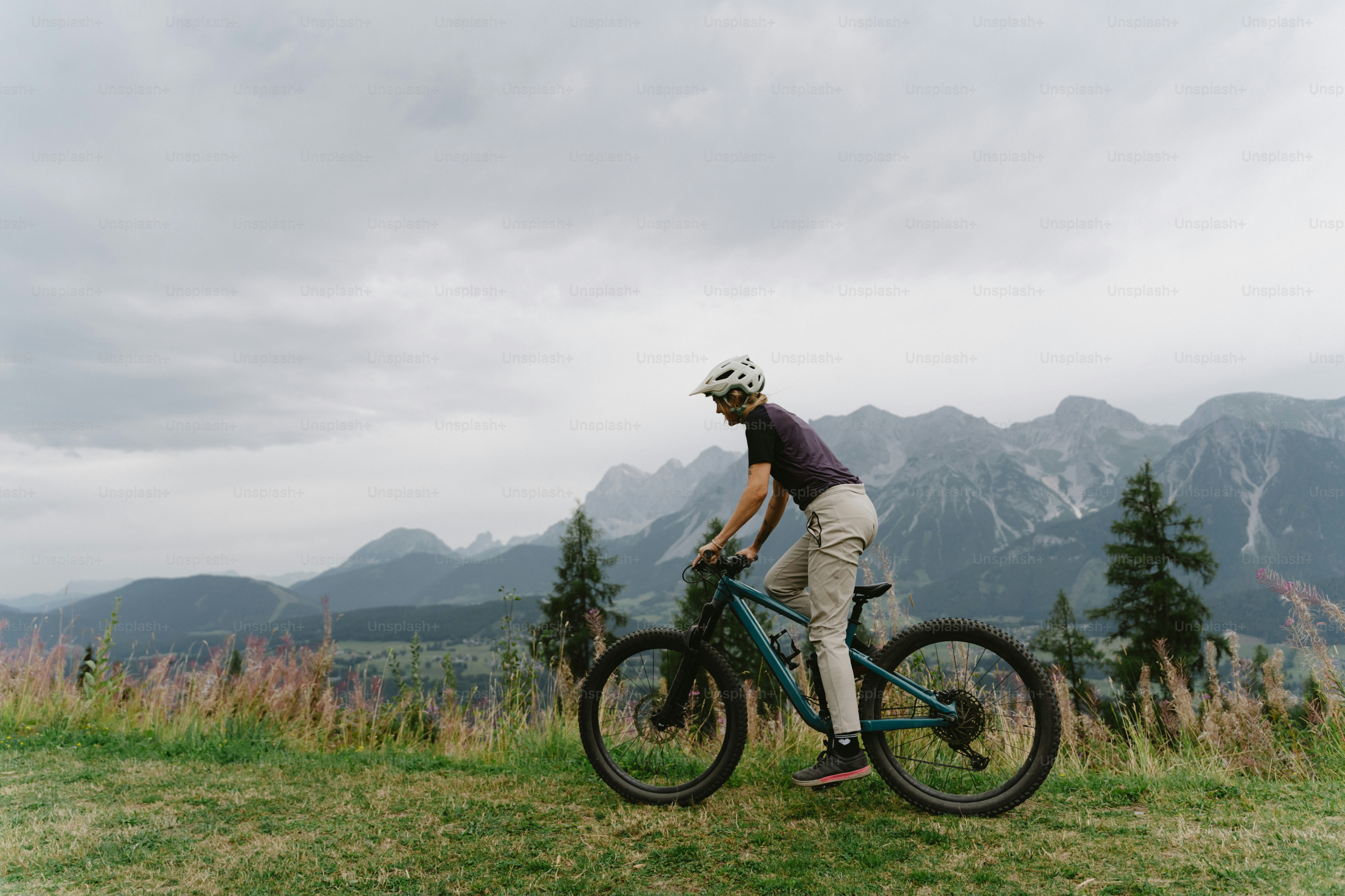 A person in a helmet cycling a mountain bike on a grassy hillside