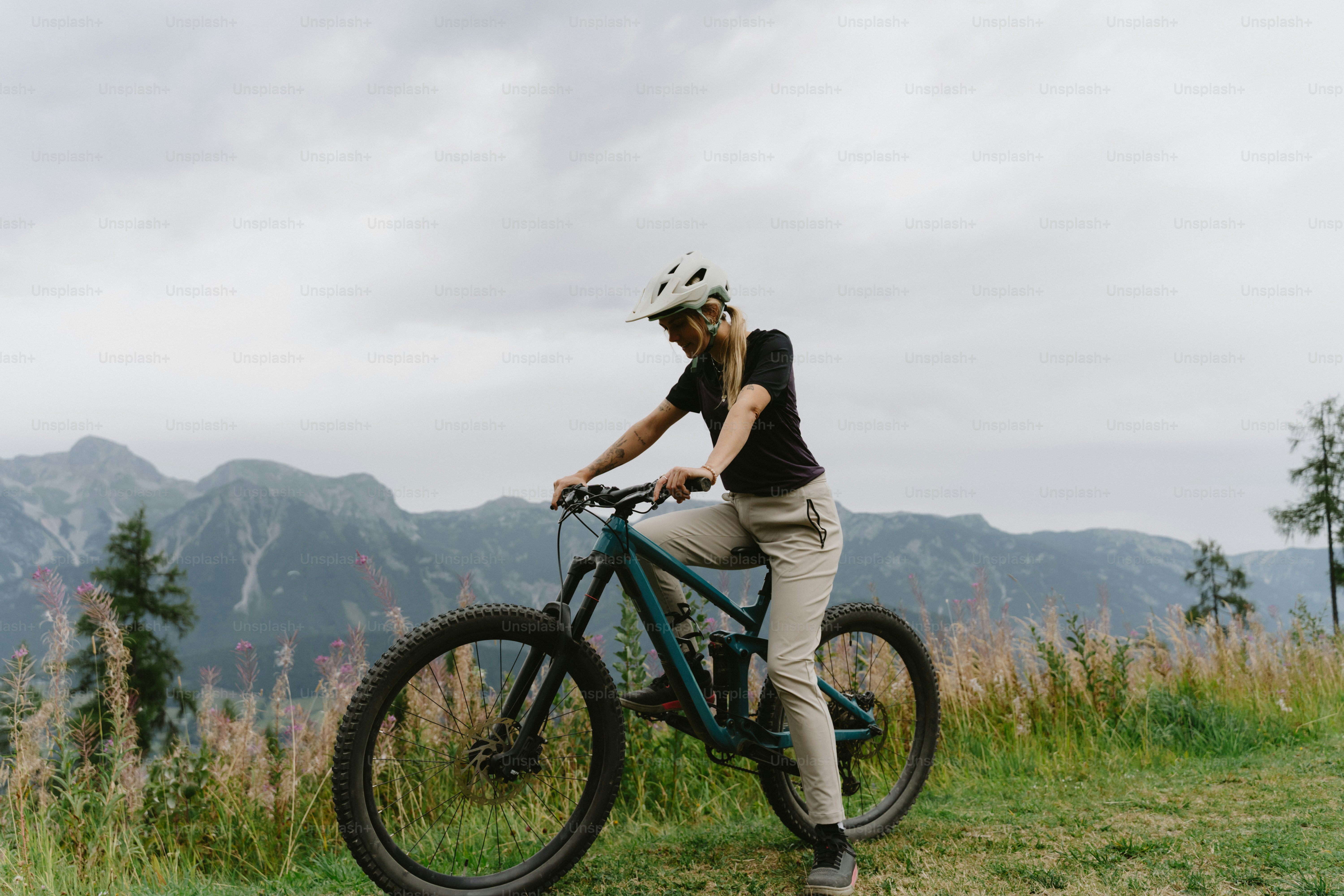 A woman in a helmet riding a mountain bike on a grassy hillside