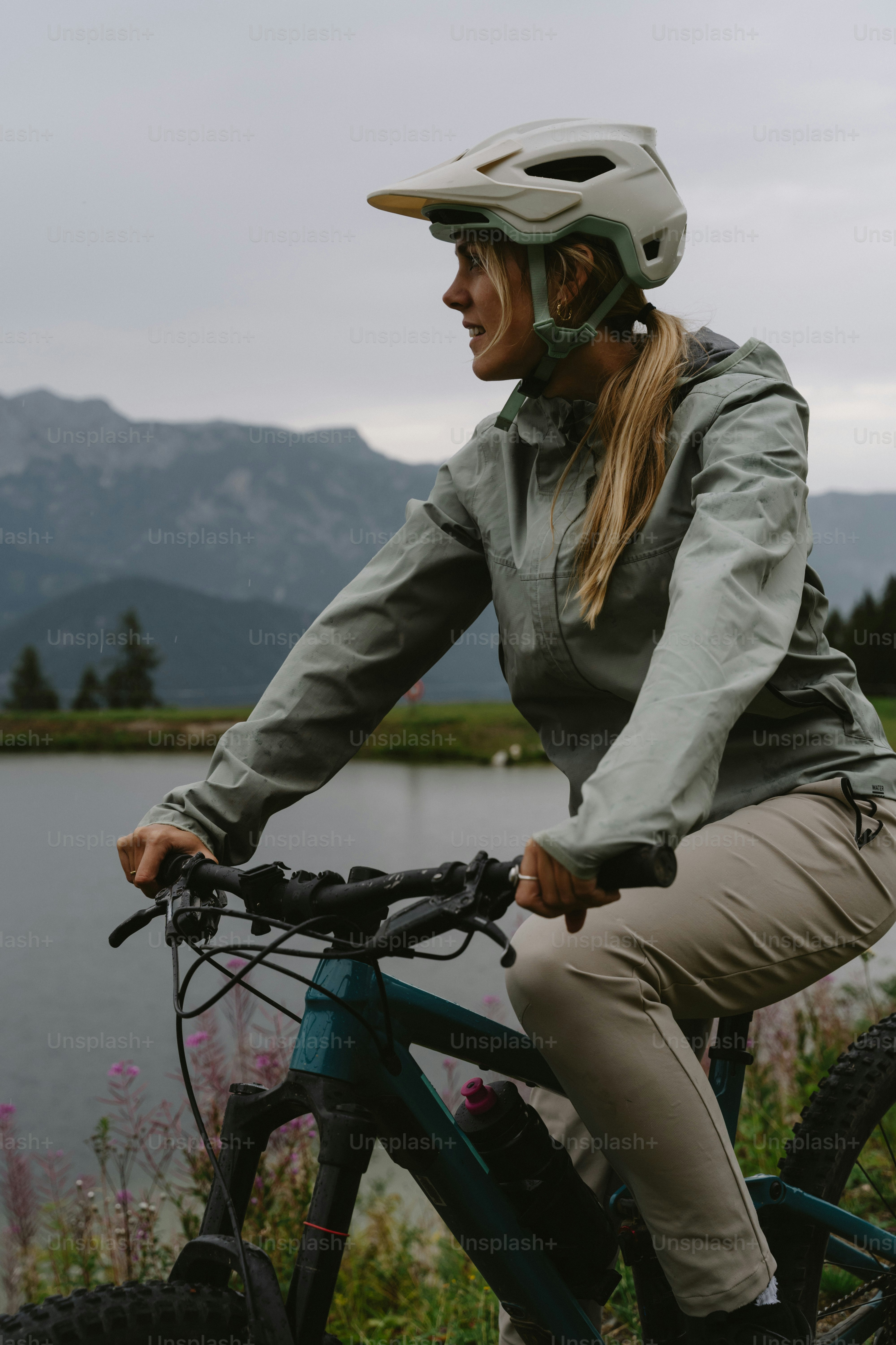 A woman in a helmet cycling on a mountain bike near a lake