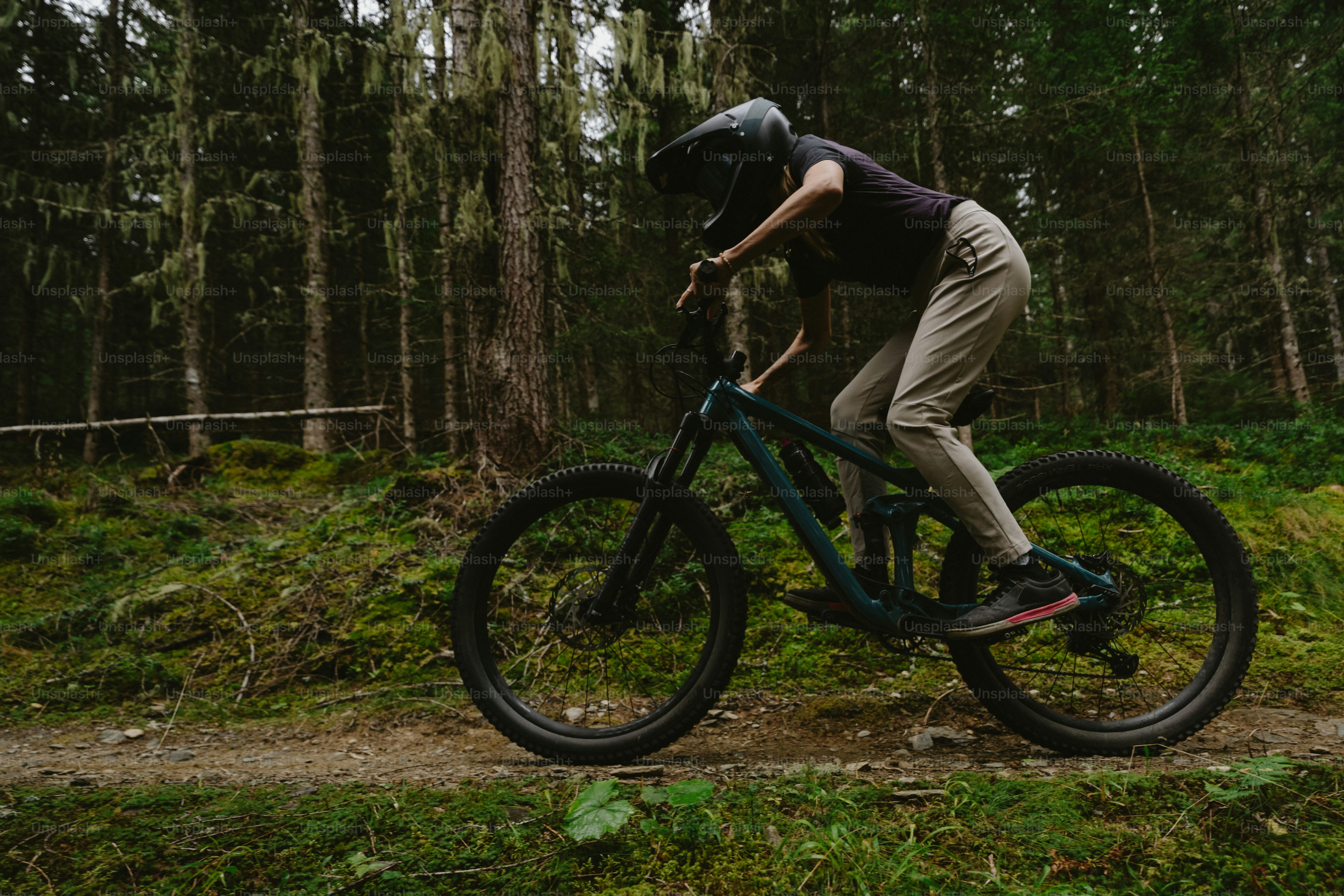 A person in a helmet cycling a mountain bike on a forest trail