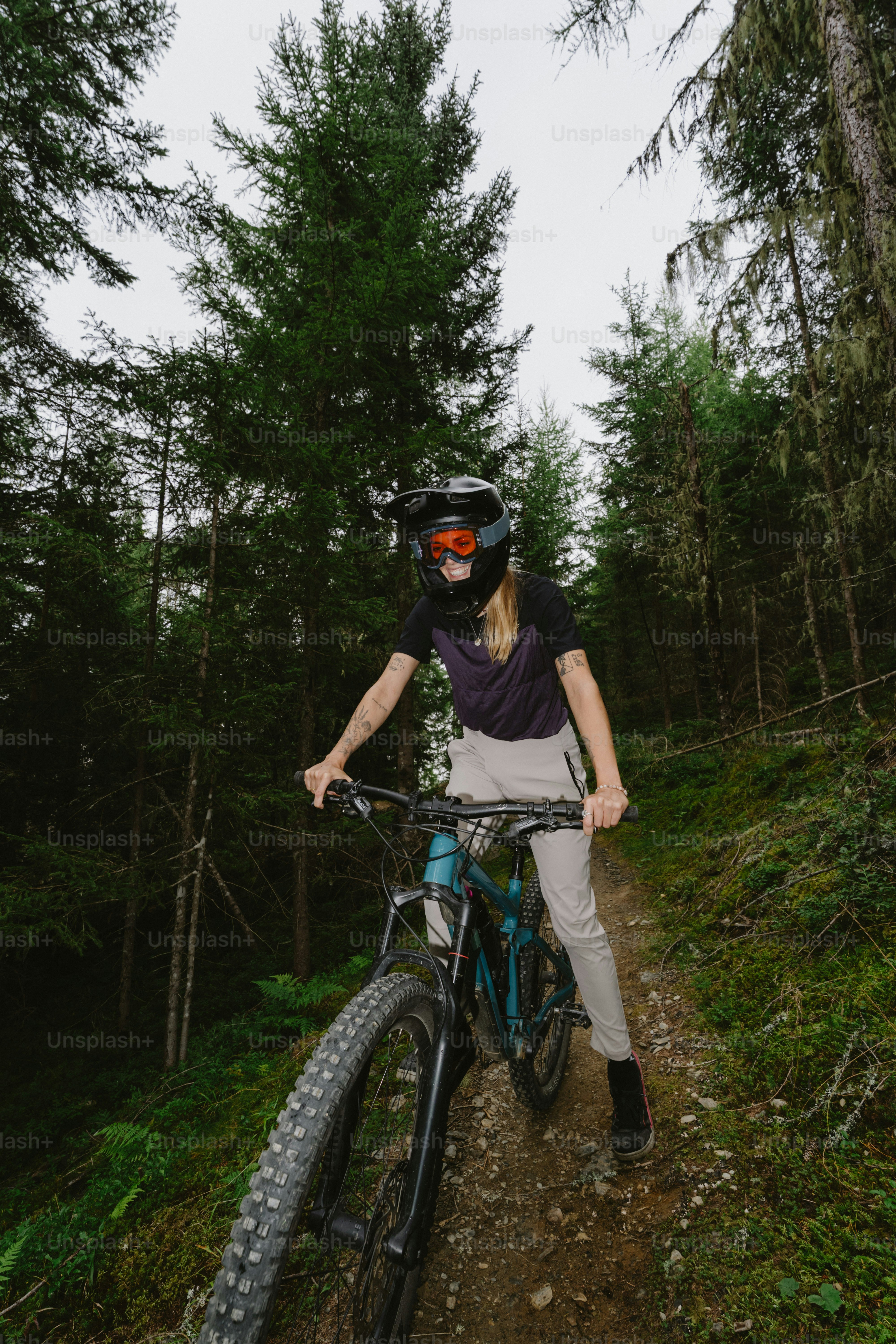 A person in a full-face helmet cycling a mountain bike on a forest trail