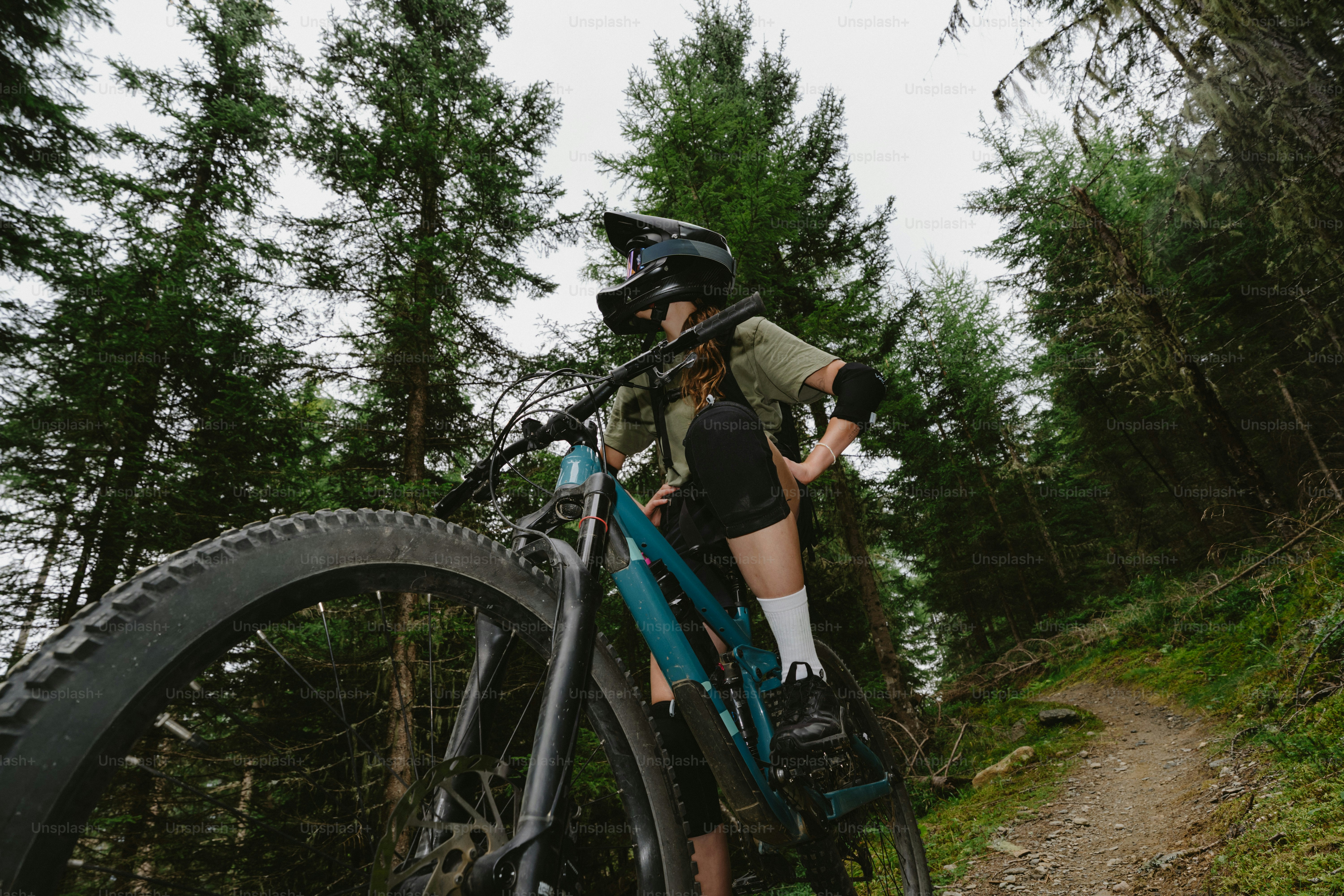 A person in a helmet and protective gear on a mountain bike in a forest