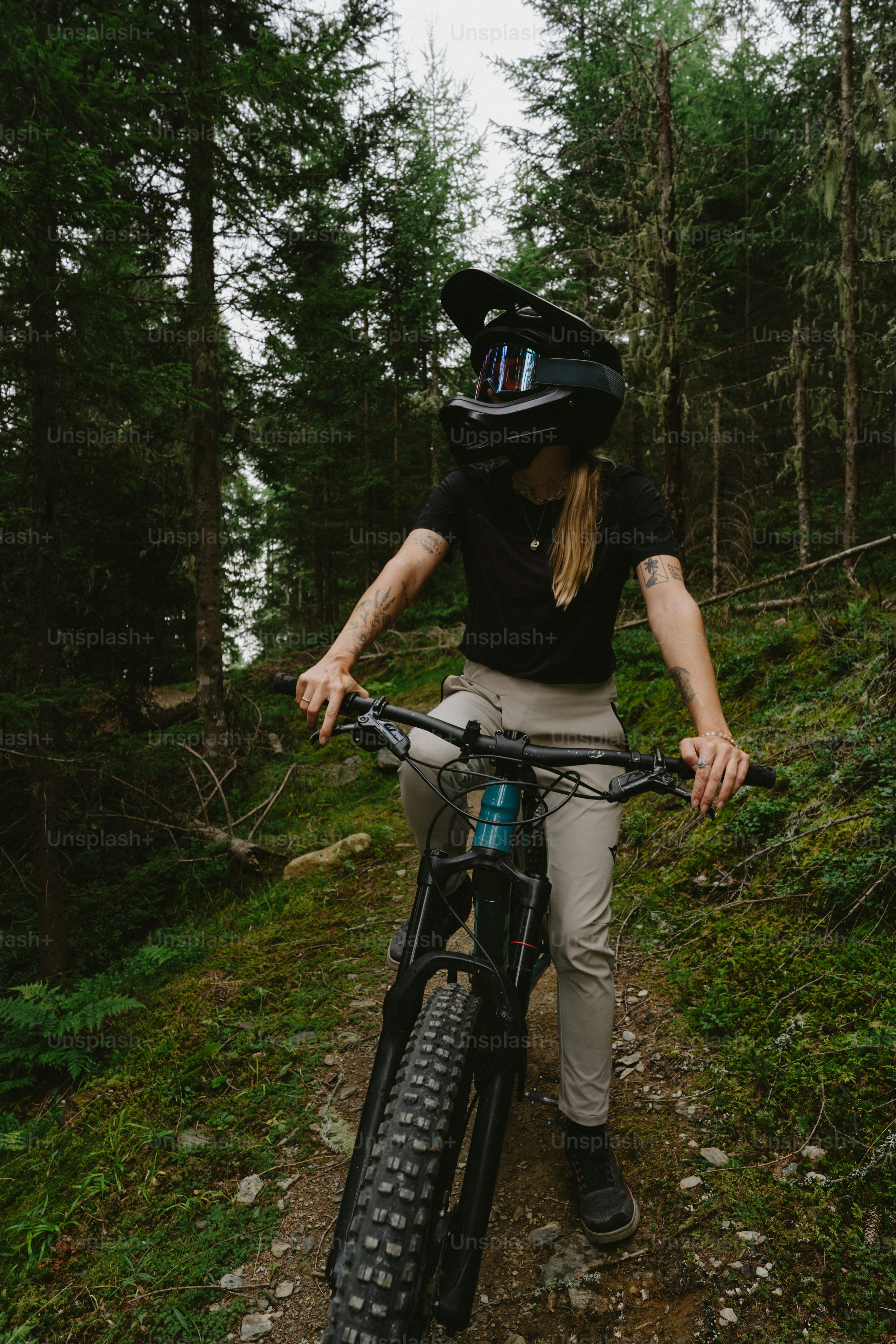 A person wearing a full-face helmet riding a mountain bike on a forest trail