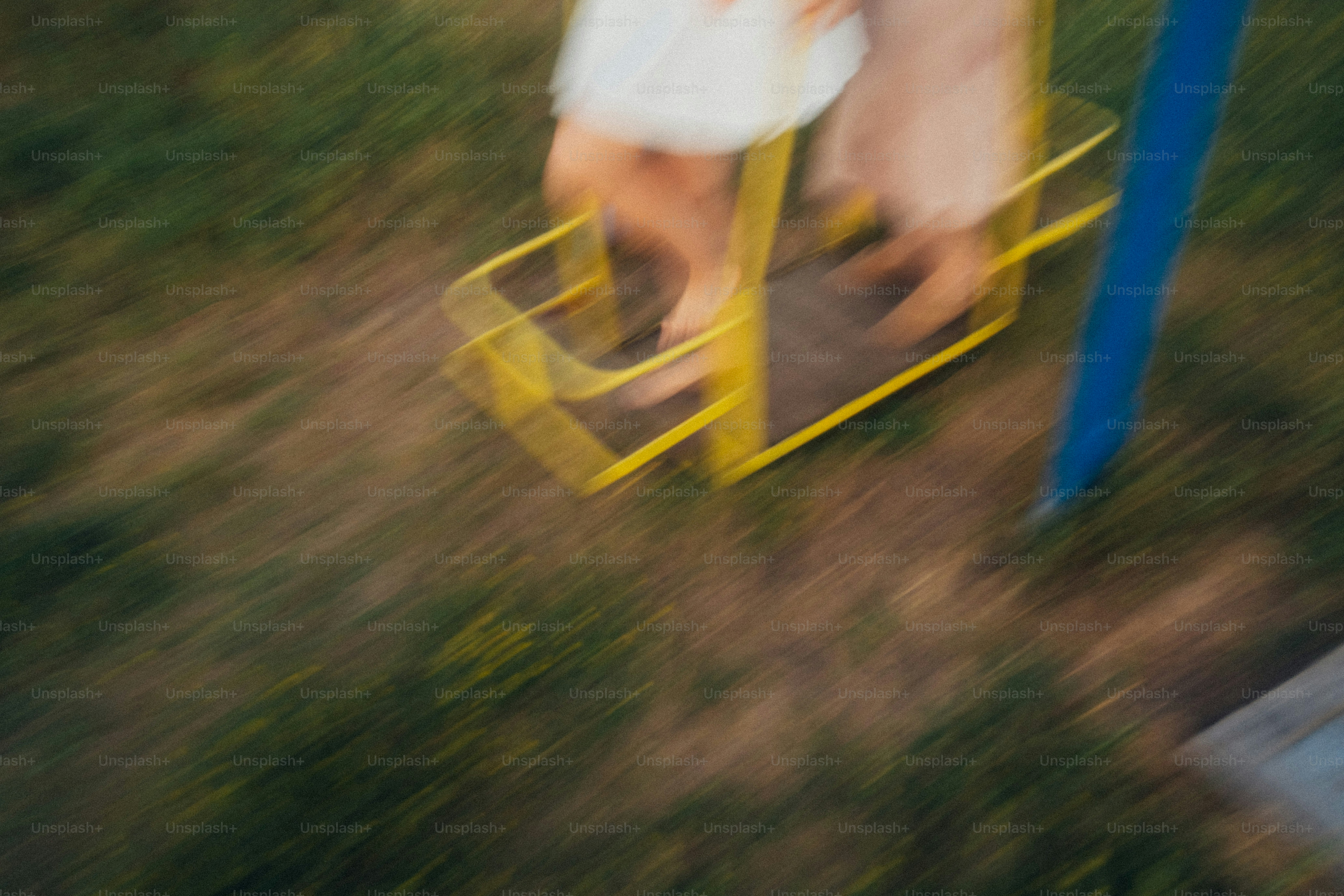 Motion blurred legs of two people on a yellow playground merry-go-round