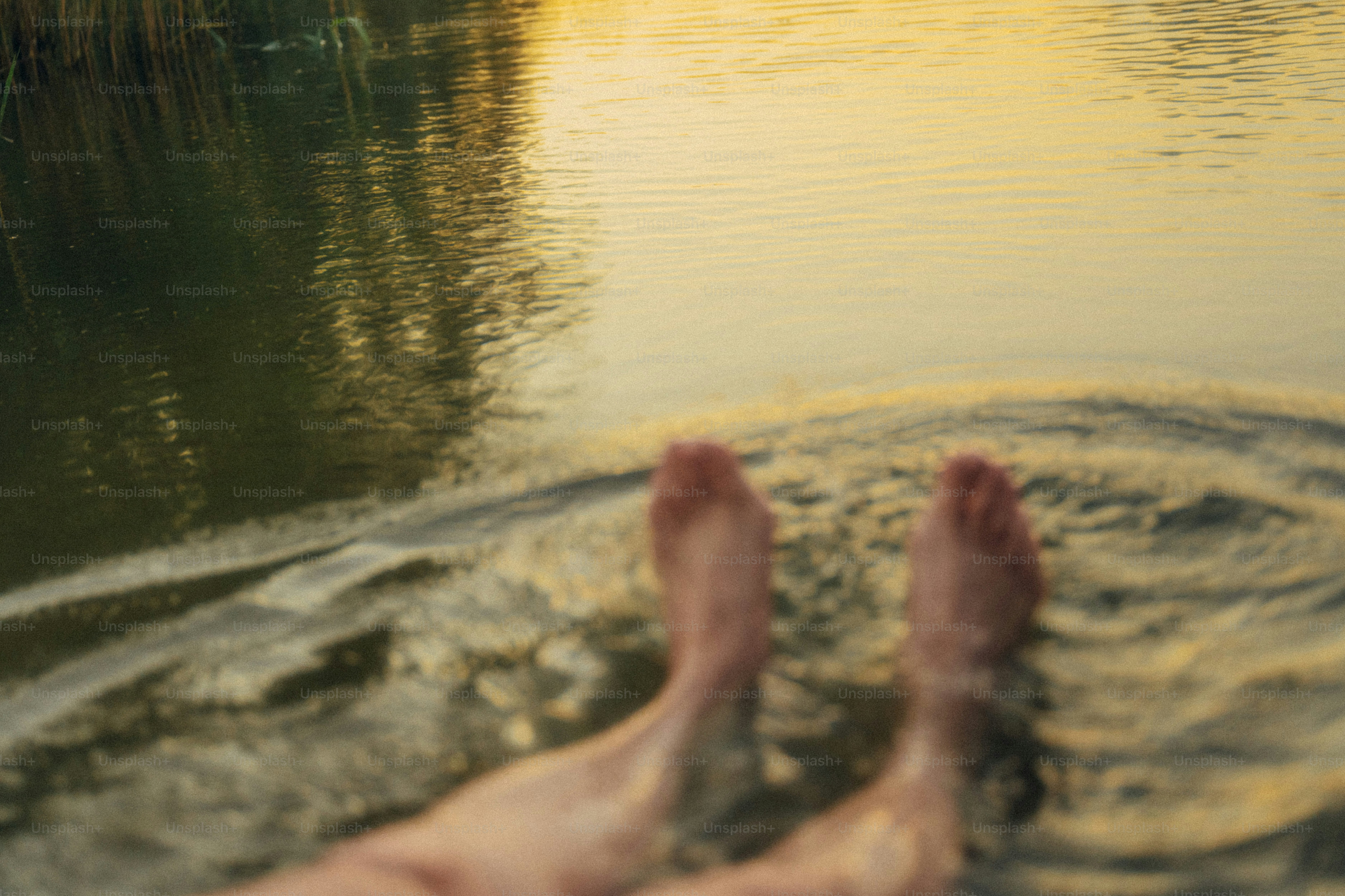 Bare feet splashing in calm water during the golden hour
