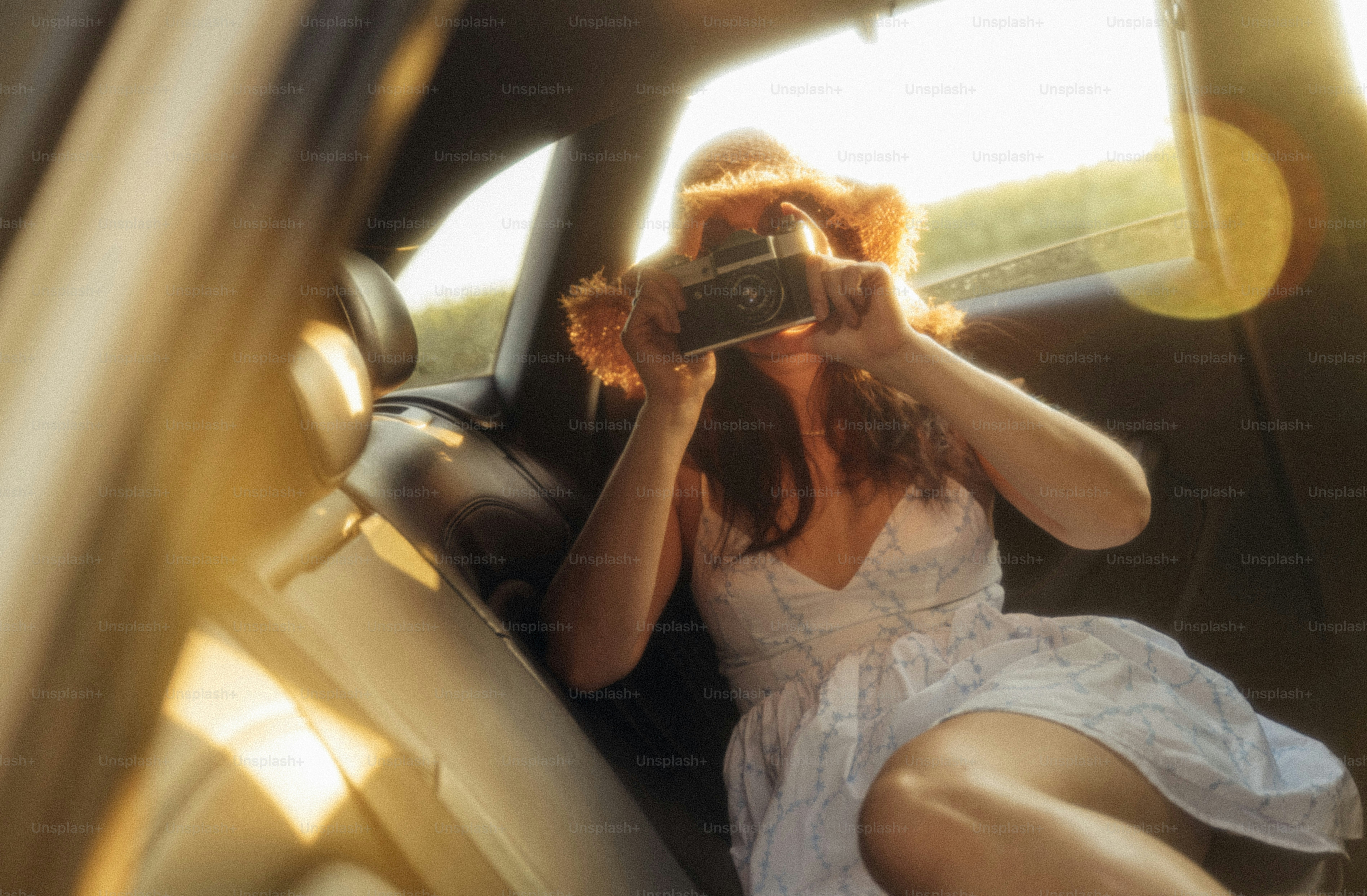 A woman holding a vintage camera in the back seat of a car
