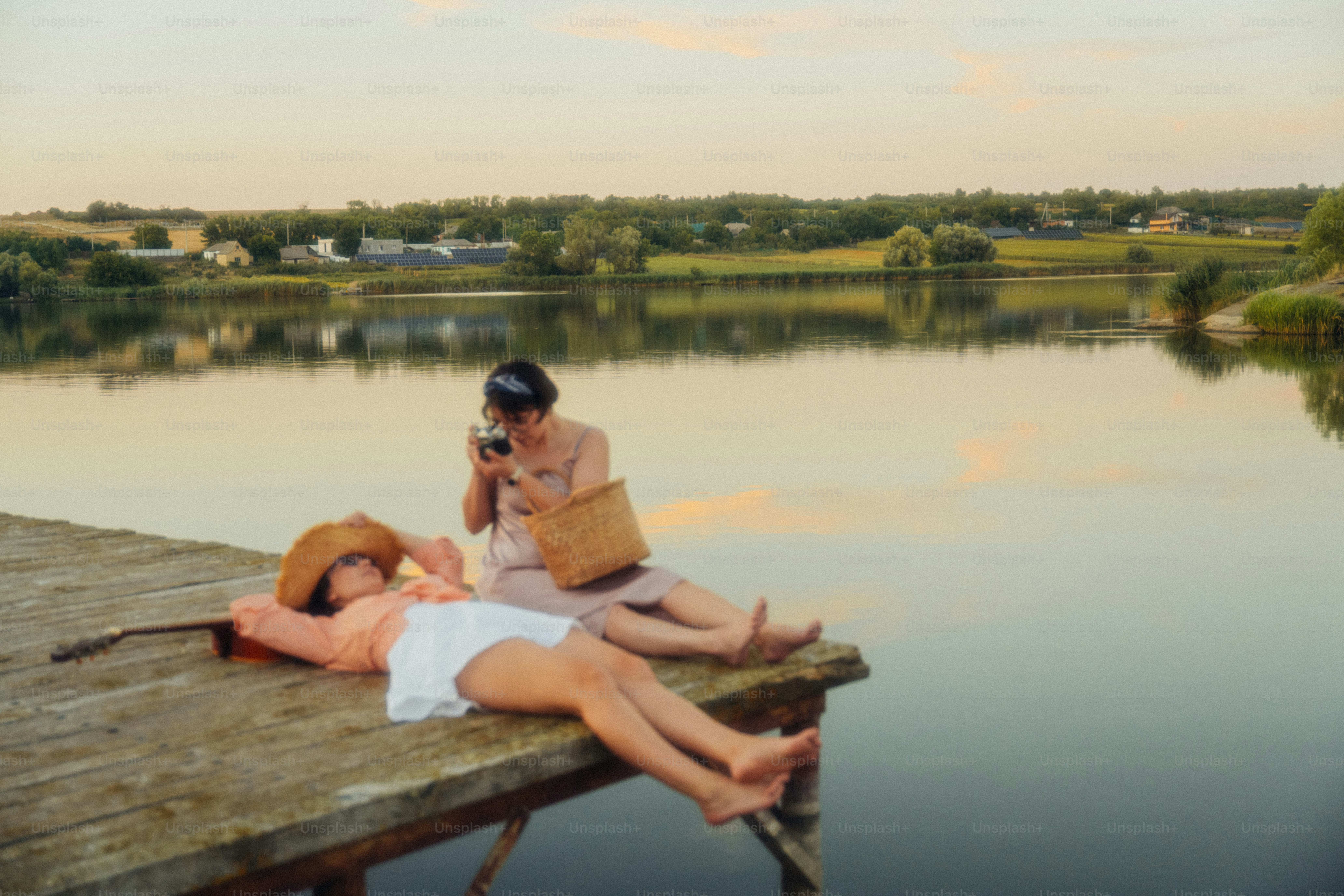 Two women on a wooden pier by a lake during the golden hour