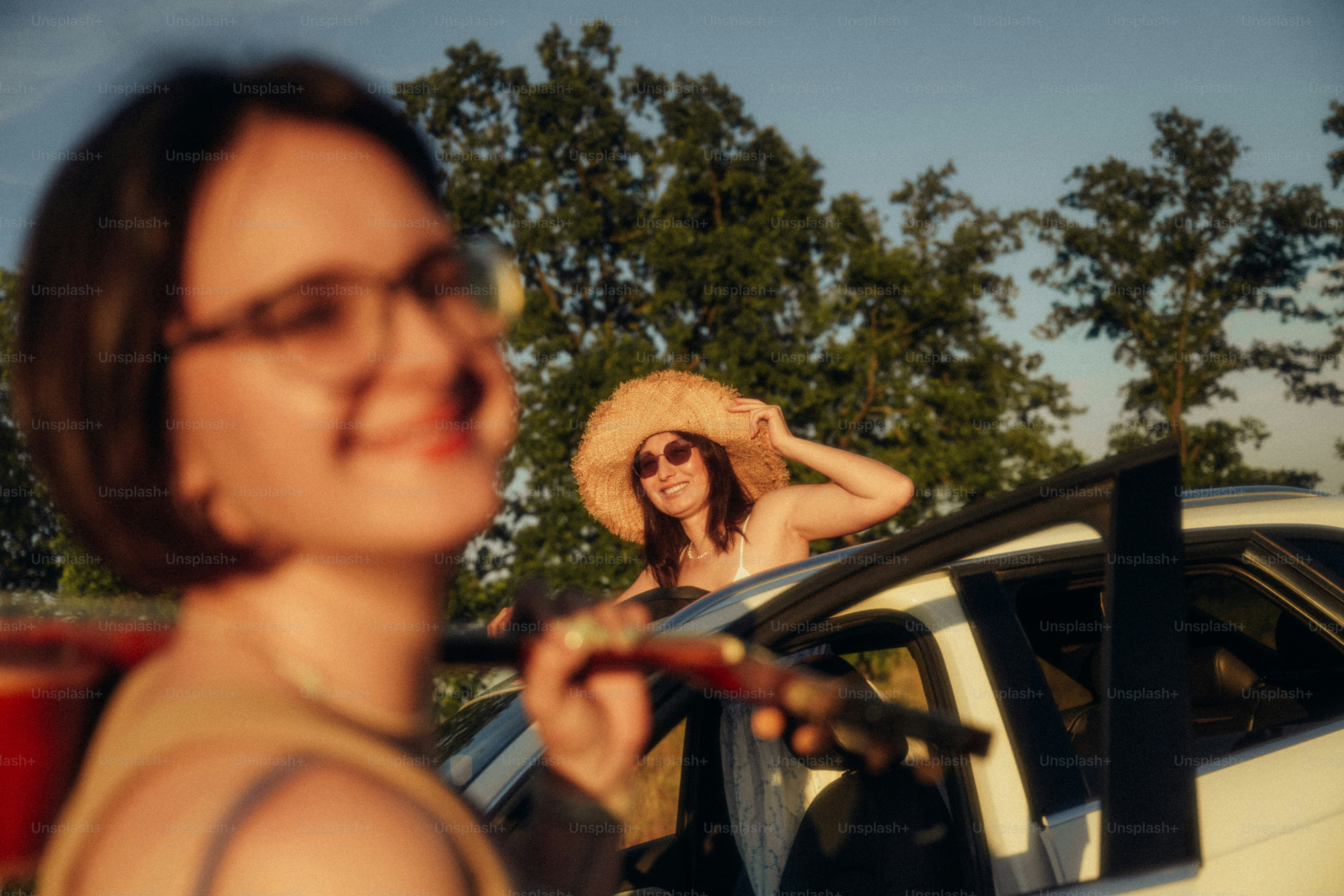 A woman in a straw hat leaning out of a car window