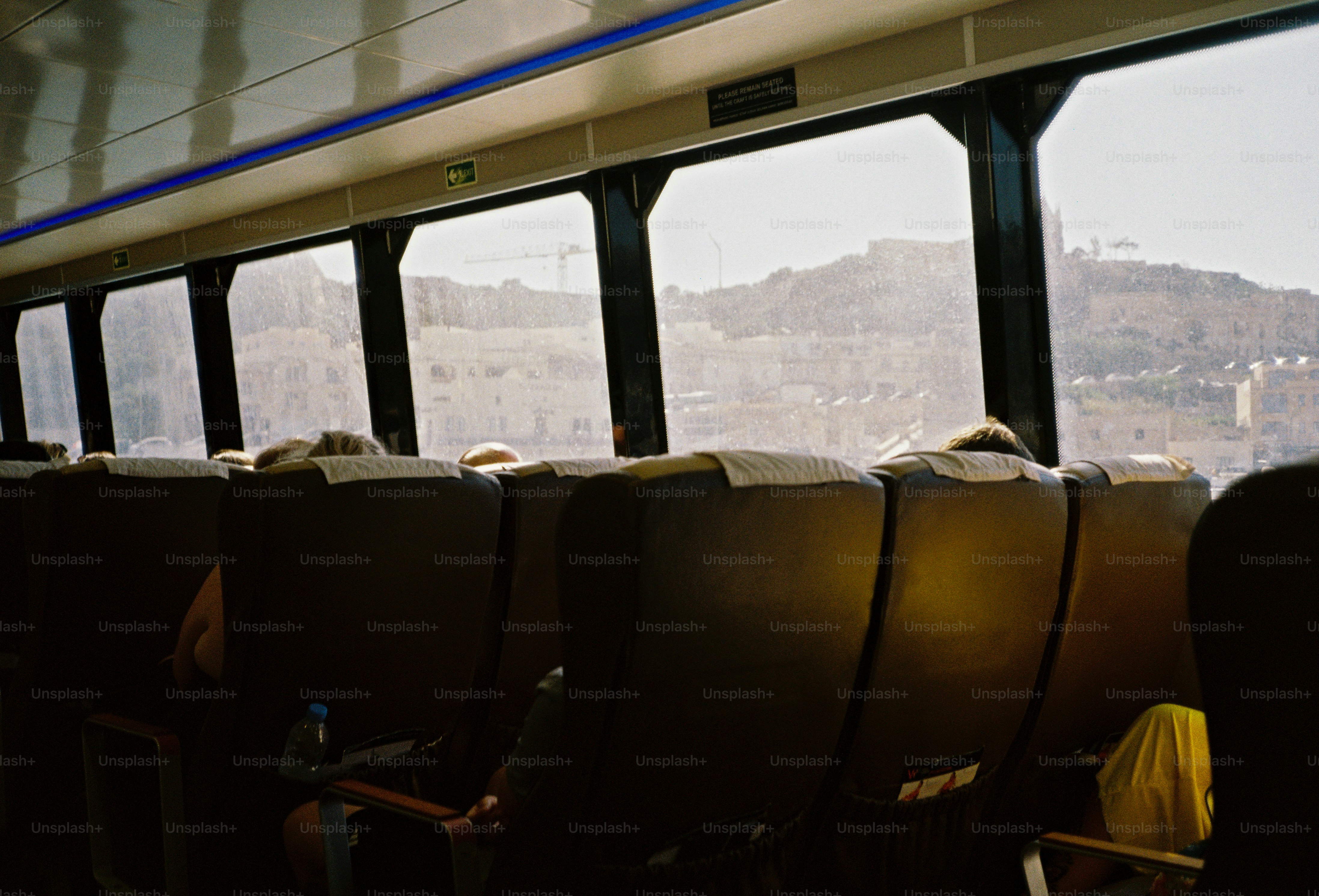 Passengers in dark seats on a ferry looking out at a coastal town