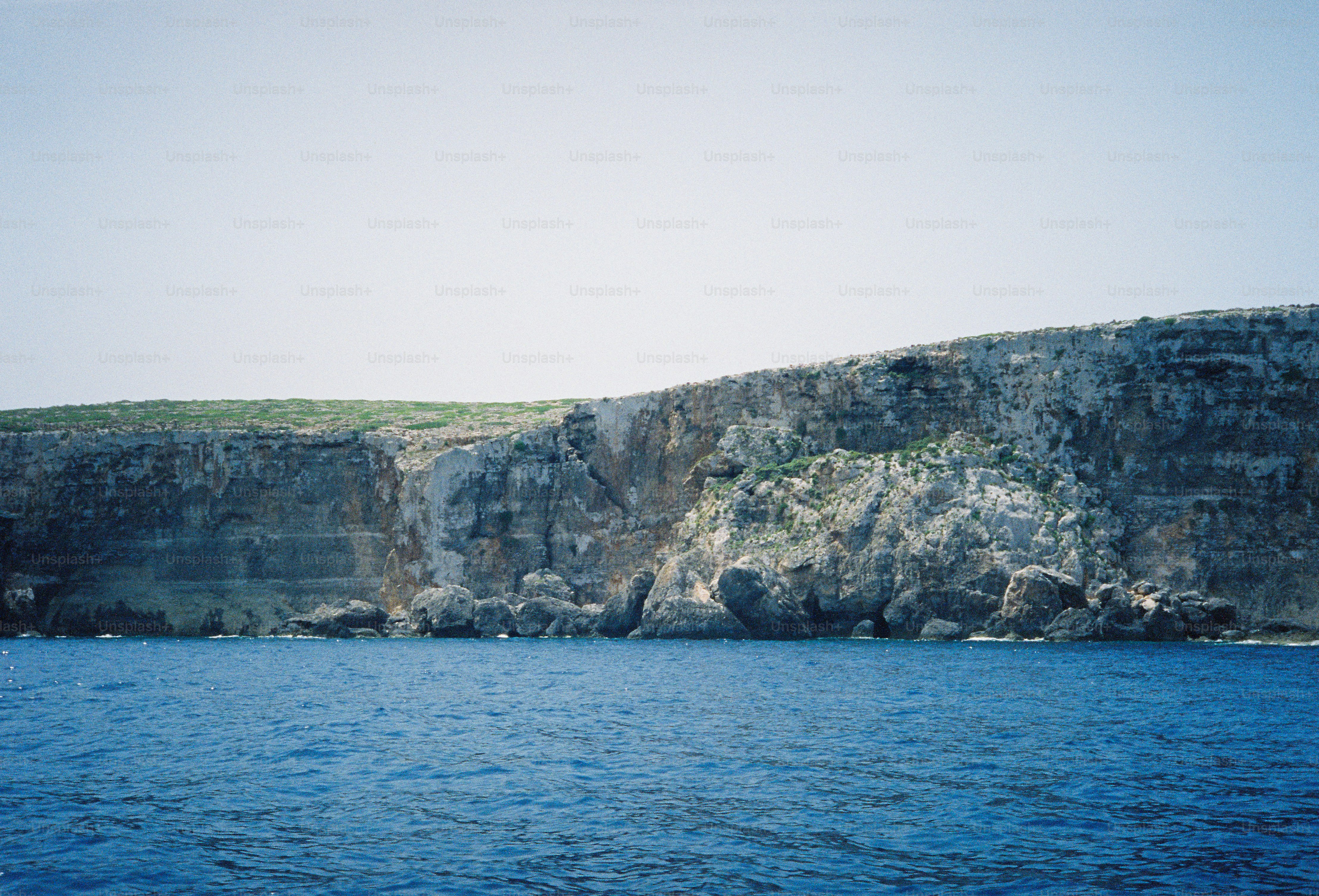 A rocky cliff face rising above deep blue sea water