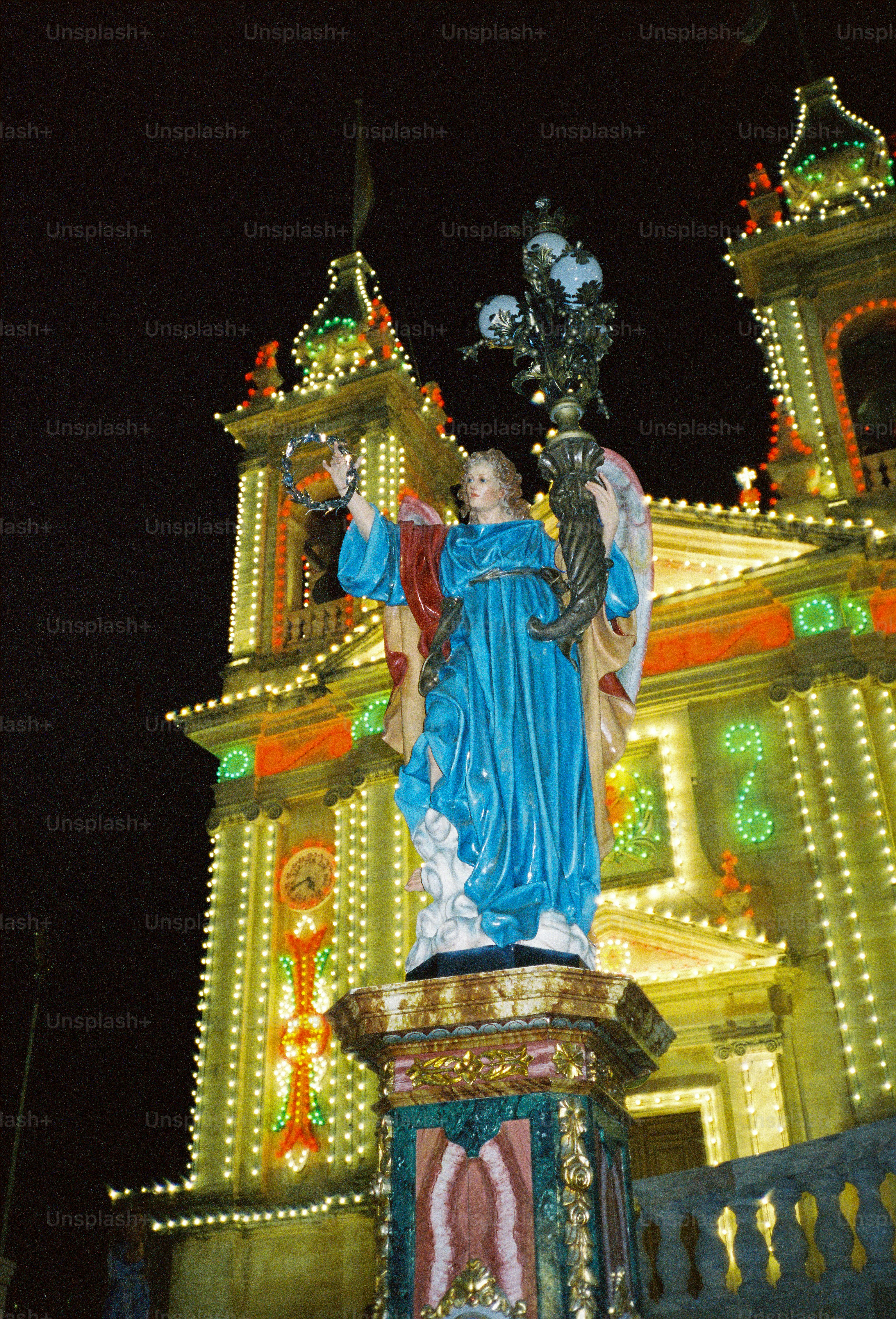 A statue of an angel holding a wreath and lamp before a lit church