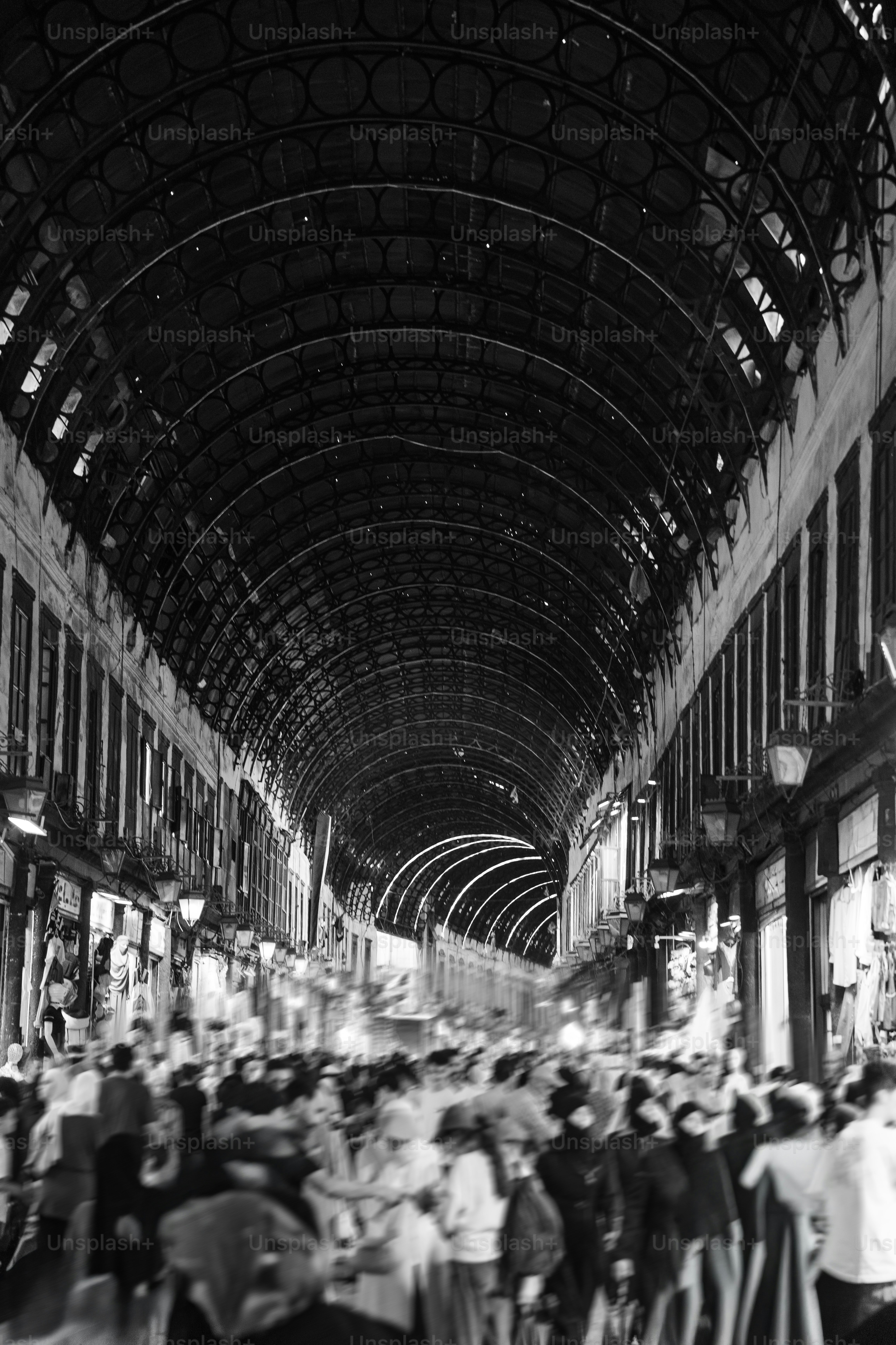 A blurred crowd of people walking through the arched Al-Hamidiyah Souq in Damascus