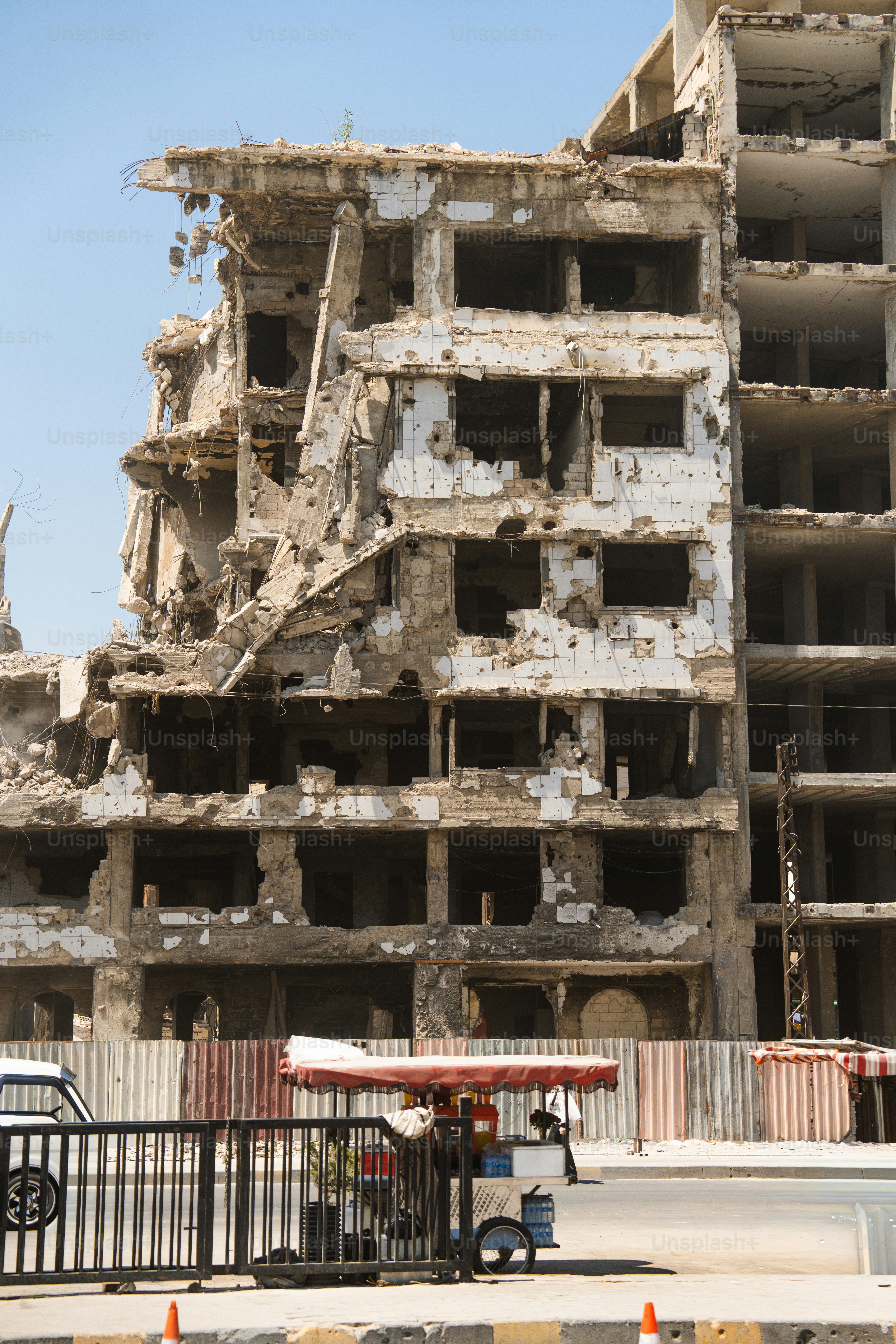 Un edificio in cemento gravemente danneggiato con barre d'armatura a vista e macerie a Homs, Siria