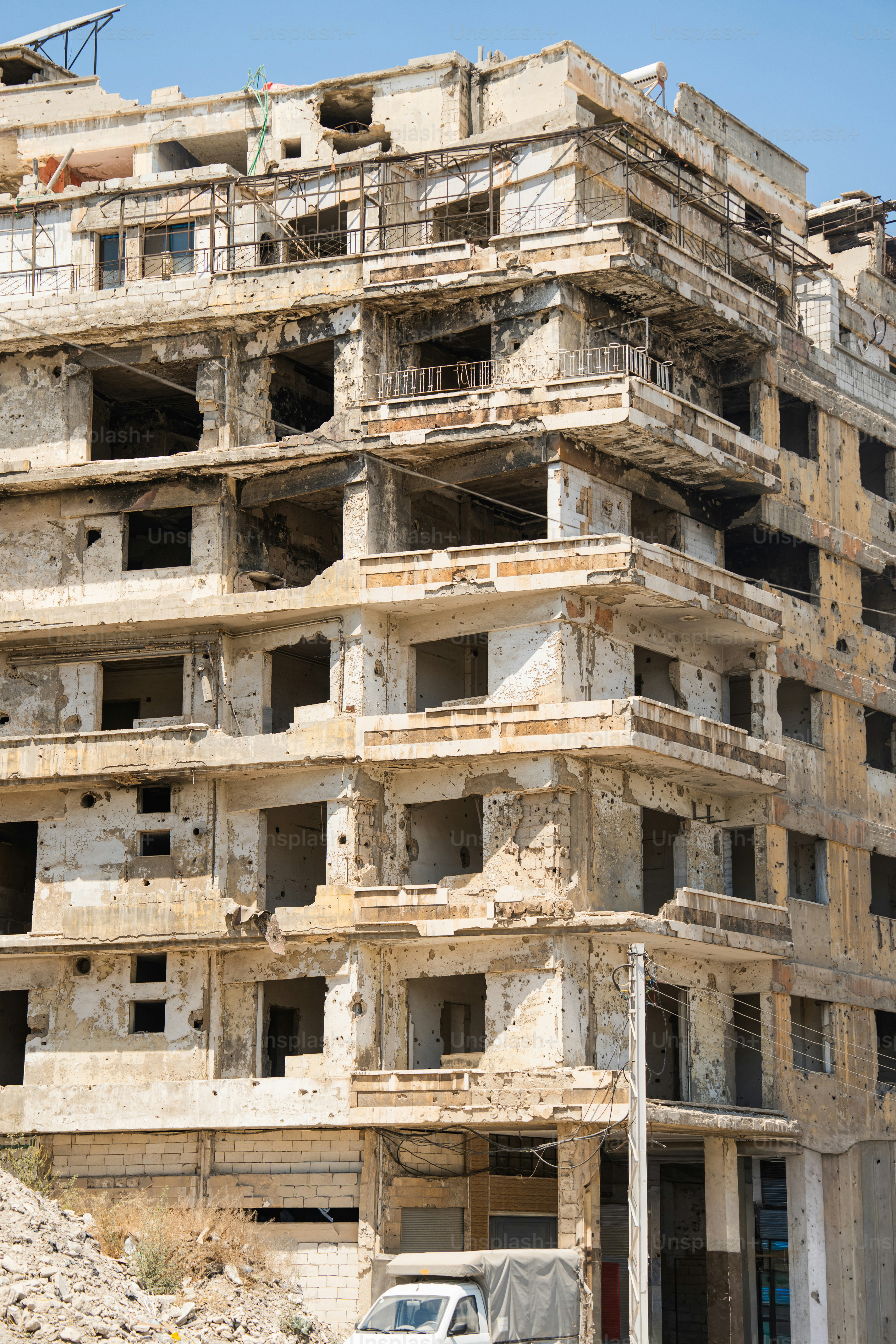 Un edificio in cemento a più piani con estesi danni strutturali e buchi di proiettile a Homs