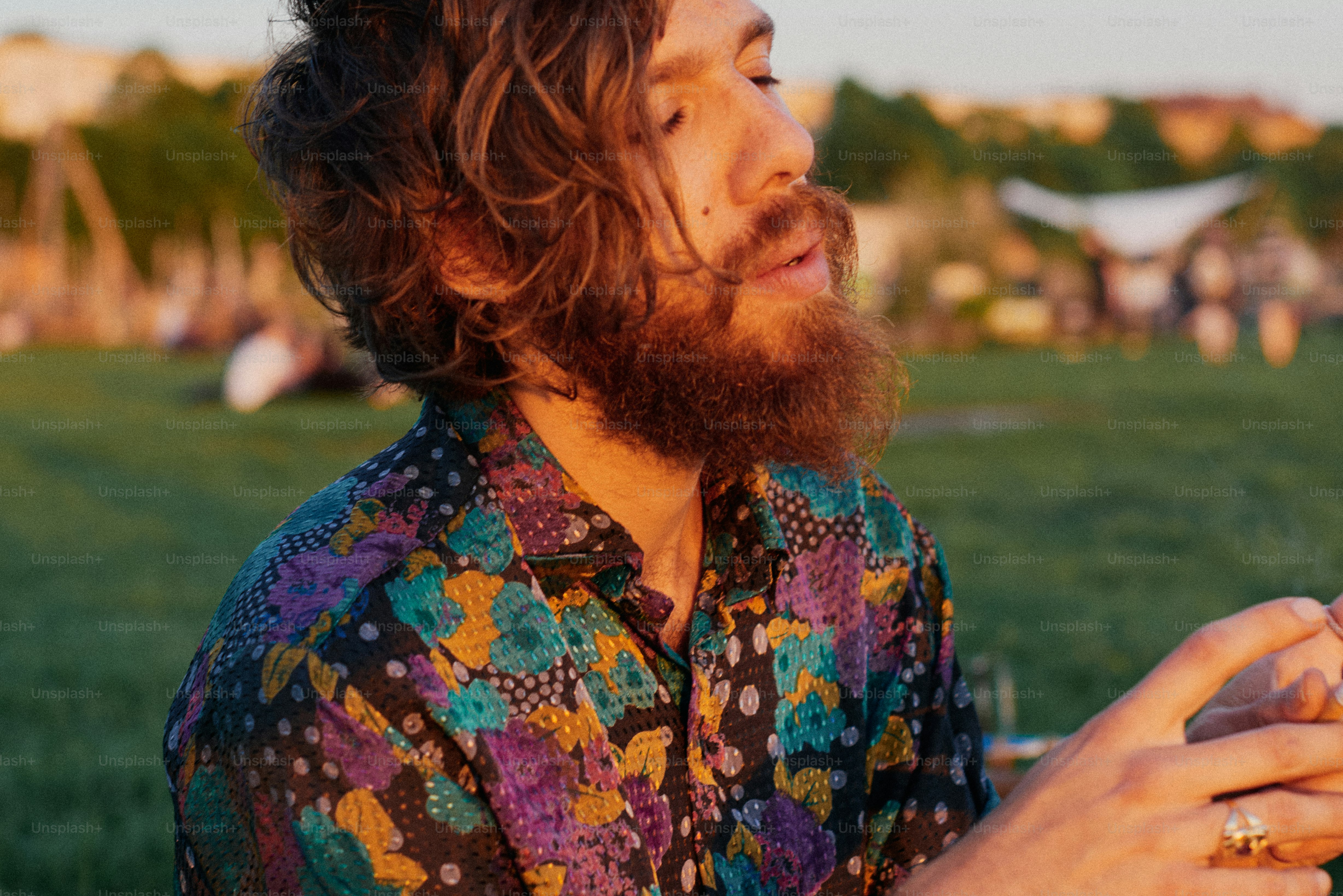 Un homme barbe et cheveux longs en chemise fleurie dehors