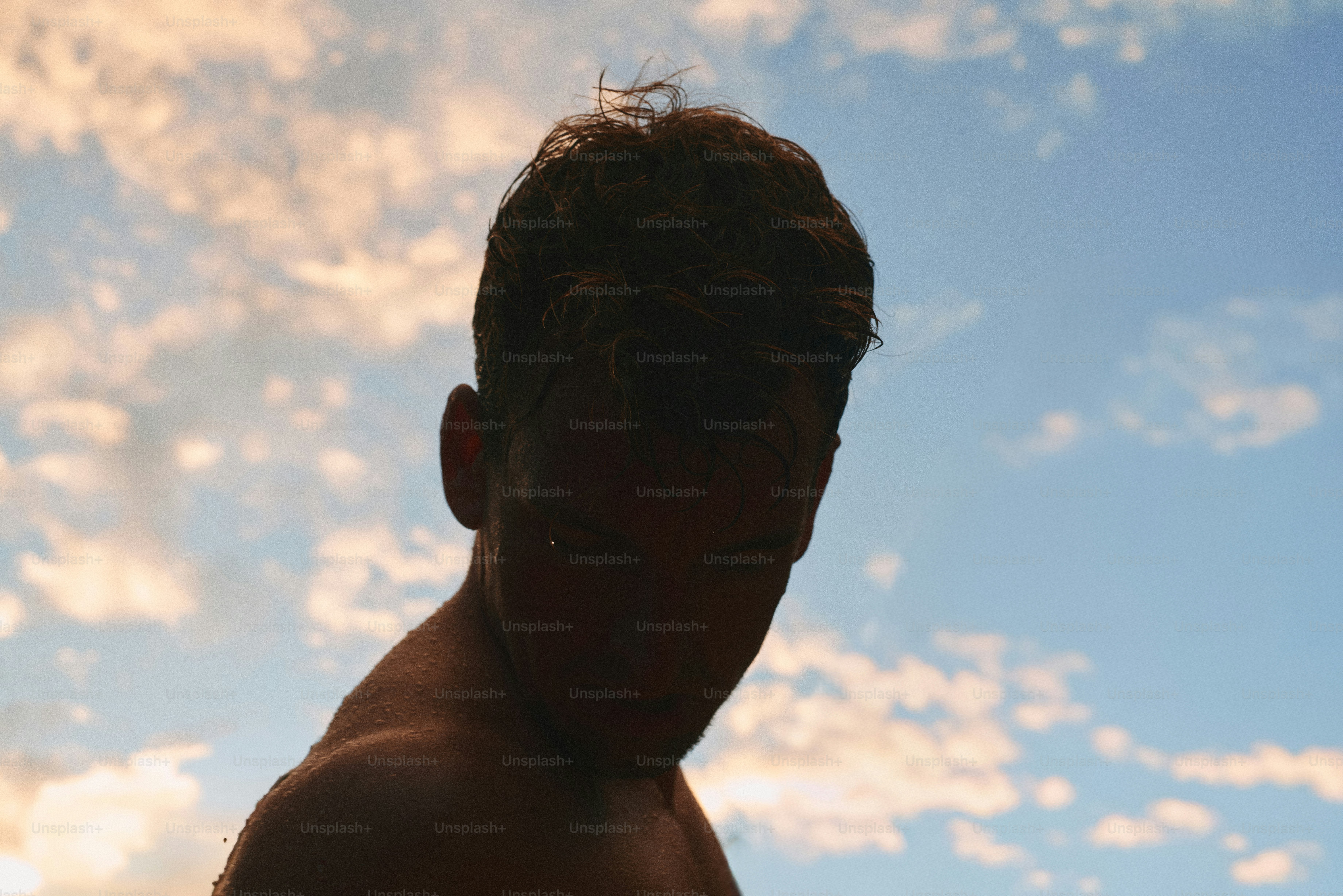 Une personne en silhouette sur un ciel bleu avec des nuages blancs épars