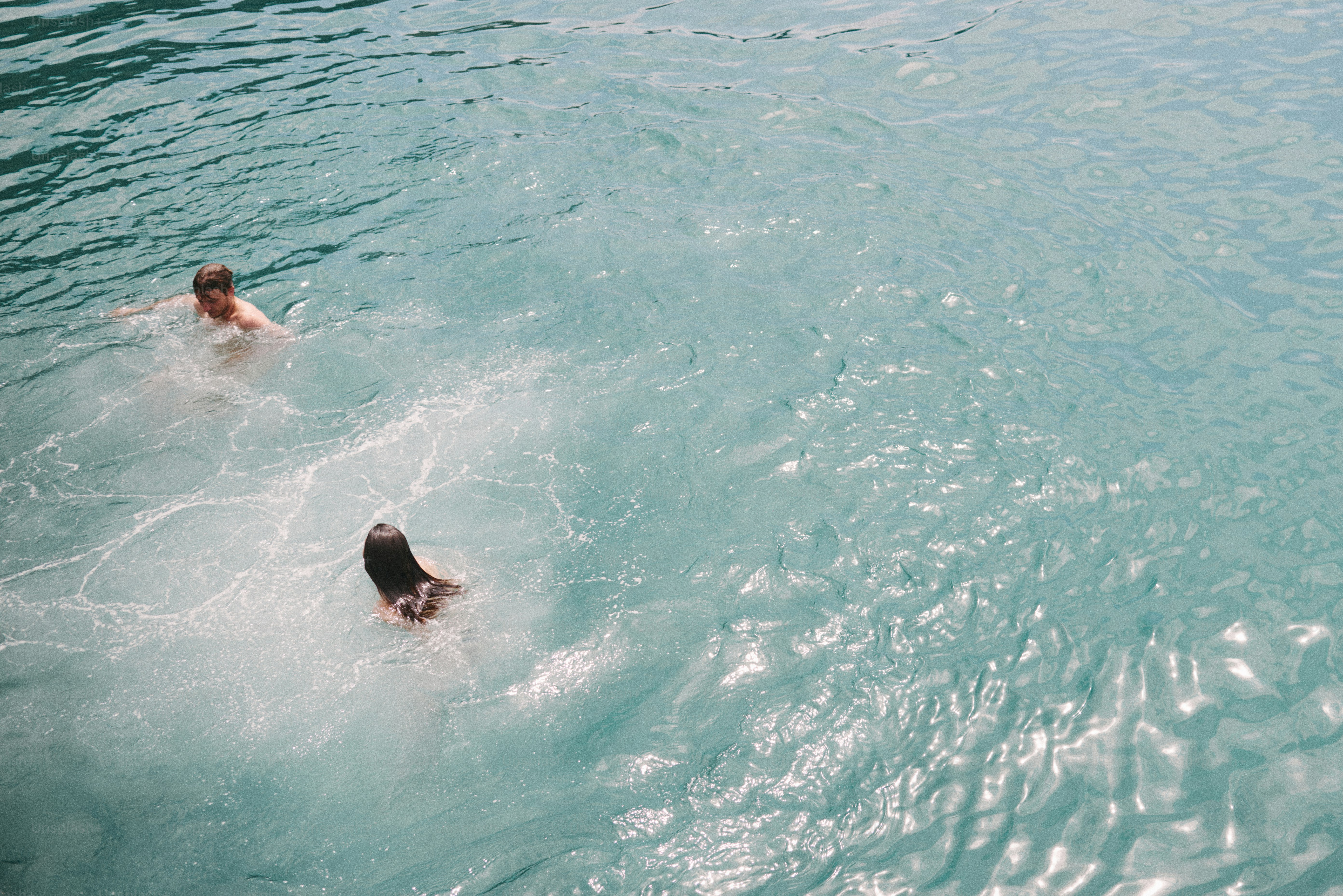 Un homme et une femme nageant dans une eau turquoise claire