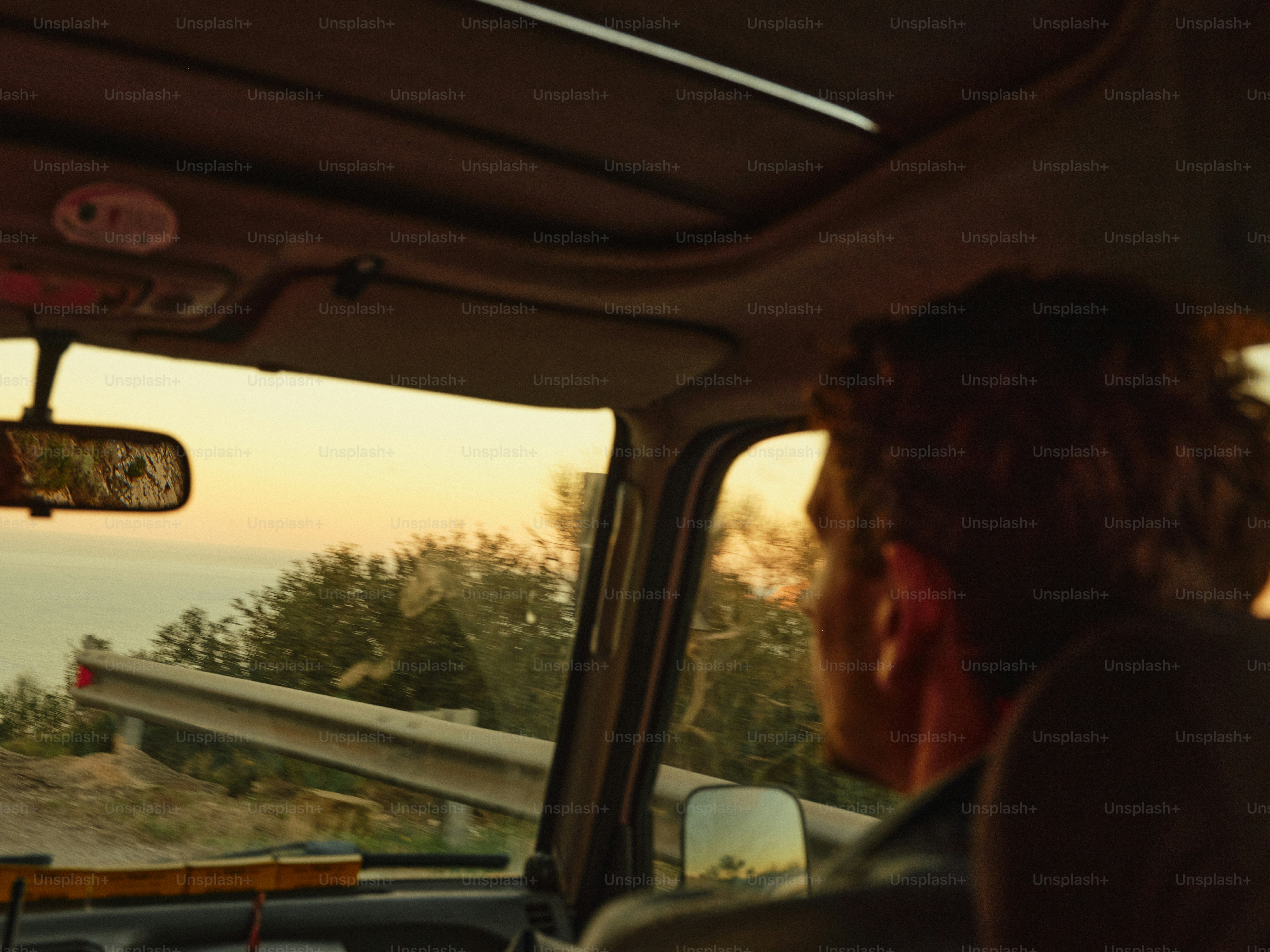 A person driving a car along a coastal road during the golden hour